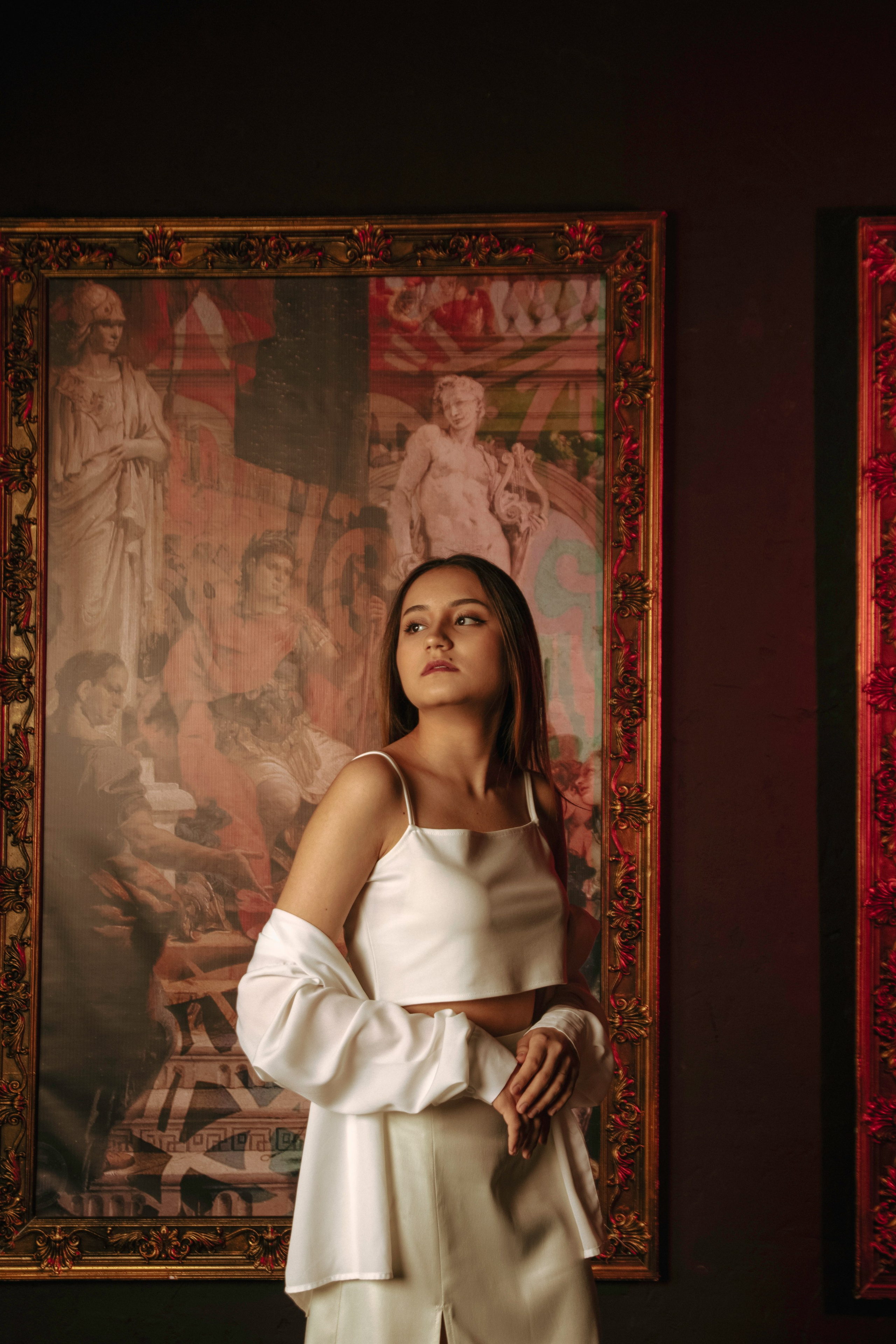 девушка позирует на фоне картин в стиле ренессанс в белой одежде