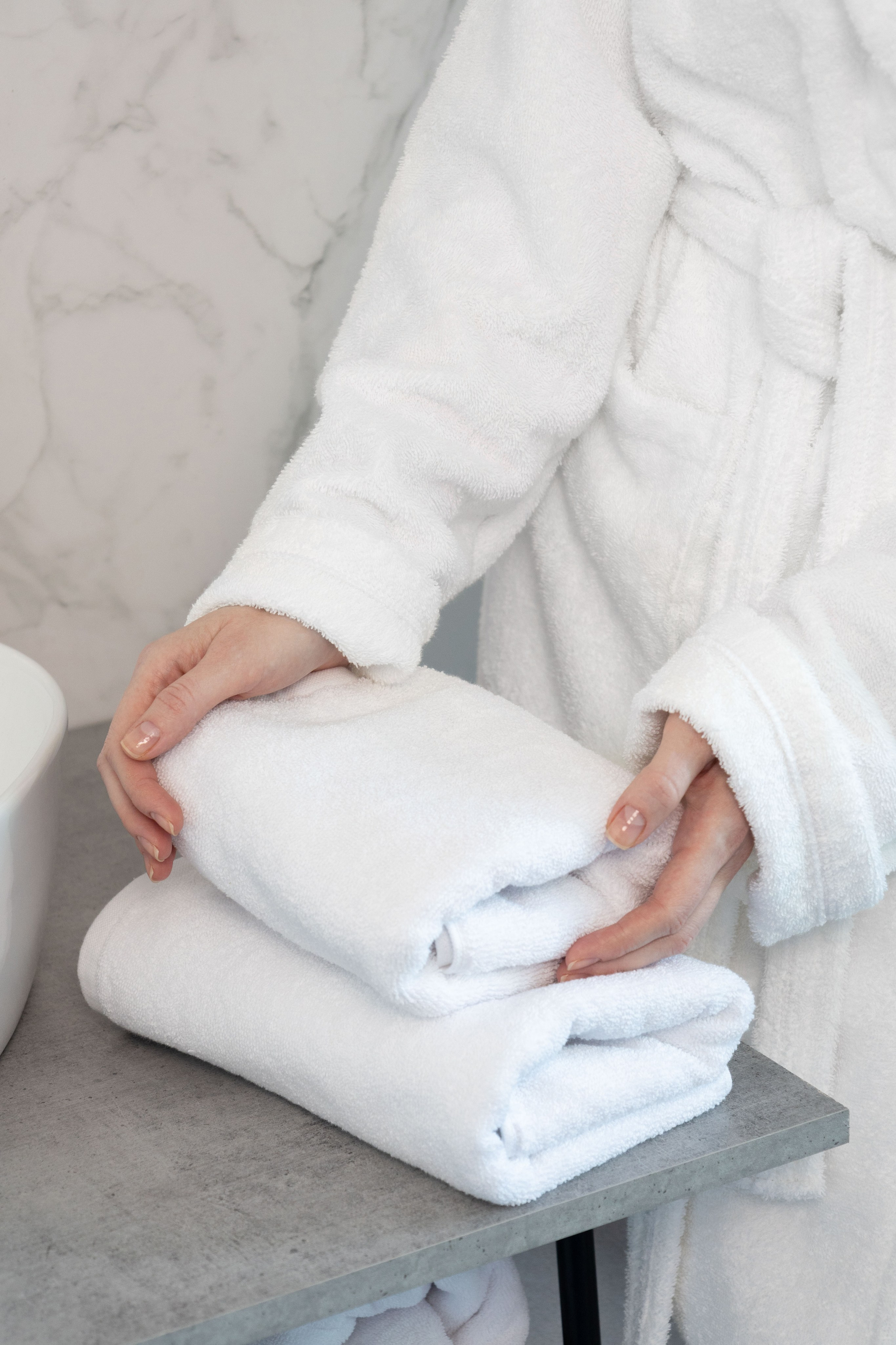 Девушка складывает белое полотенце | Съемка для каталога