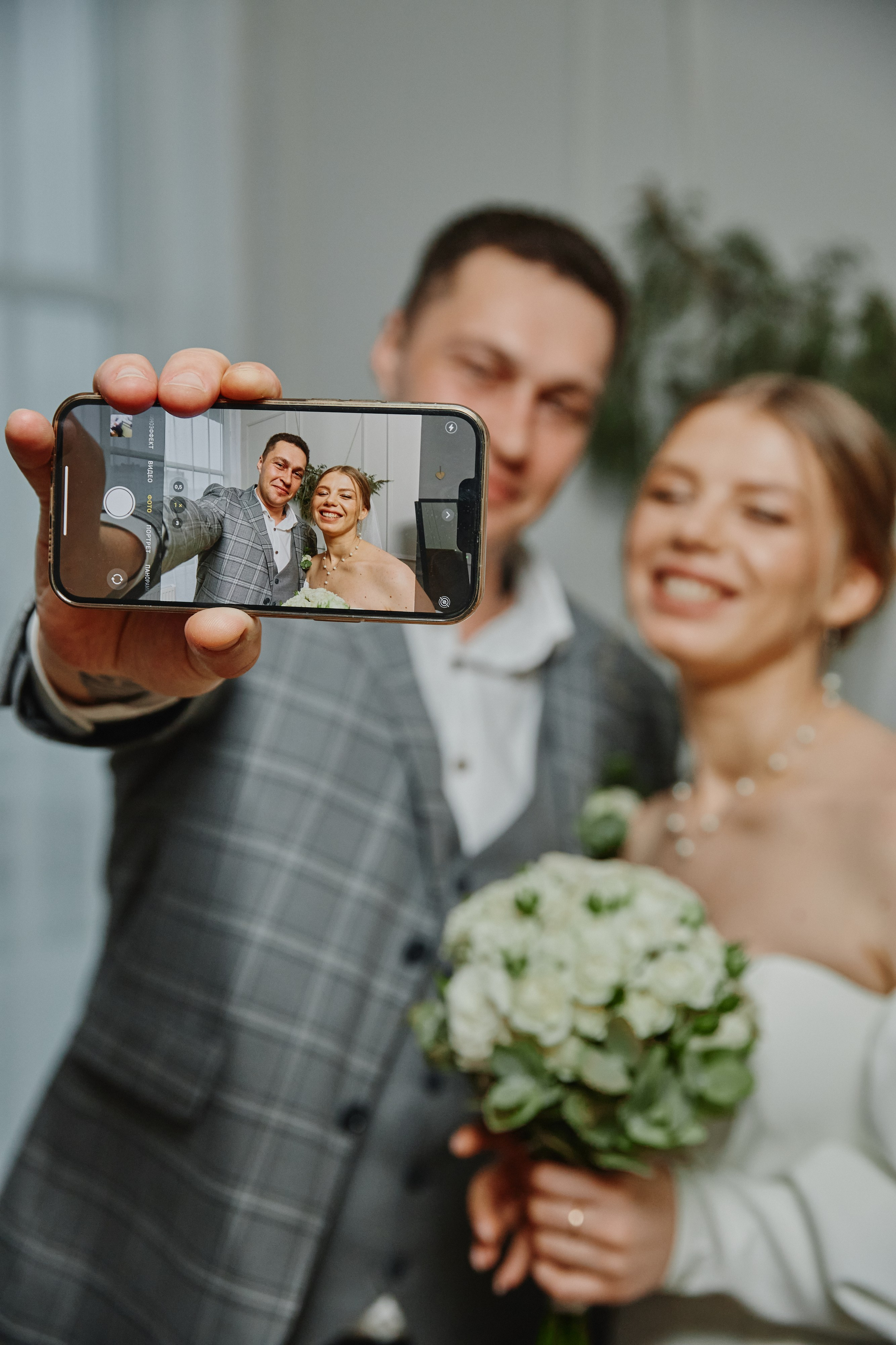 Жених и невеста делают селфи в фотостудии