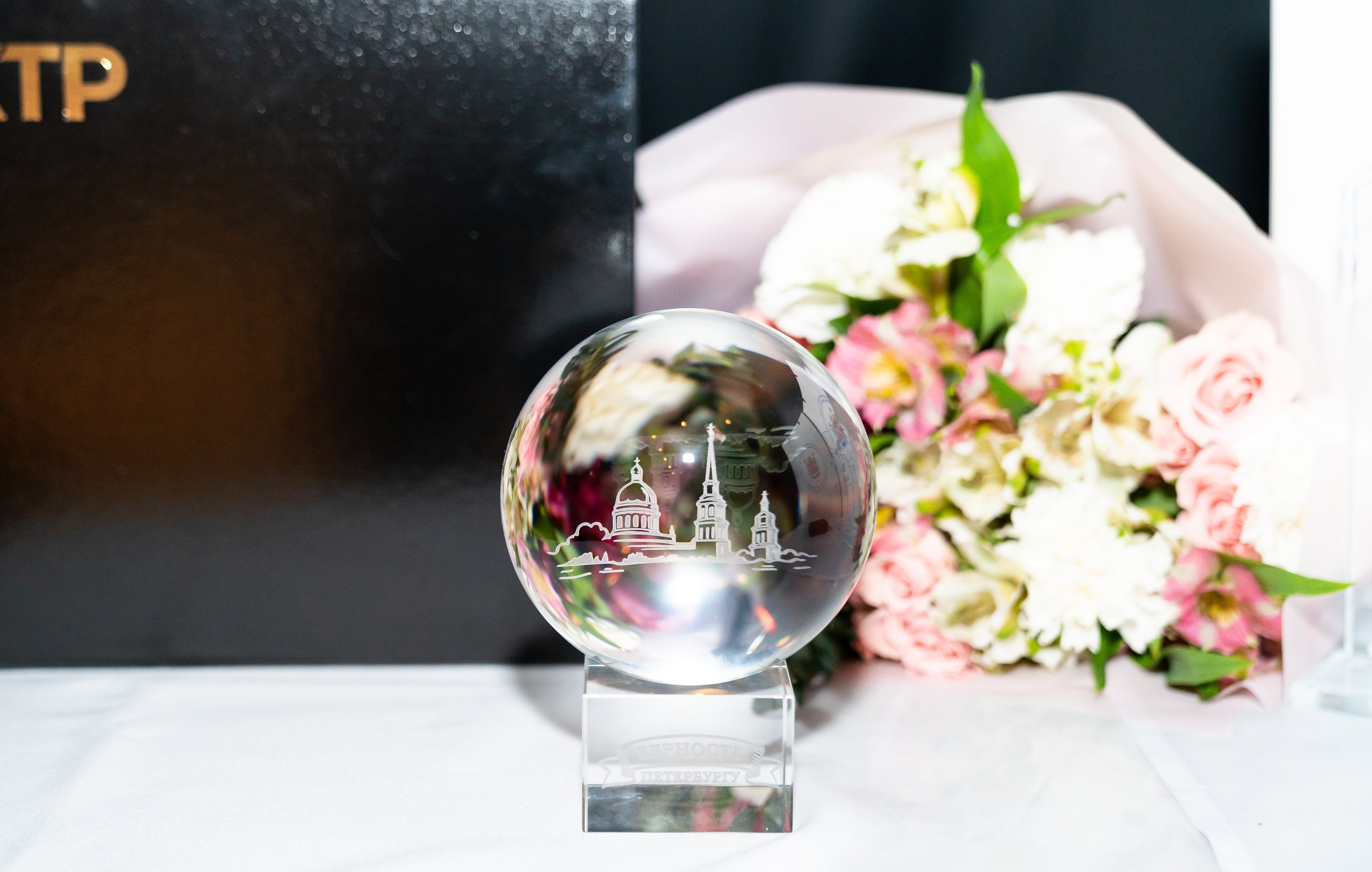 Медаль и хрустальный приз «Лучший муниципальный служащий Санкт-Петербурга 2026». Букет цветов и награды КТР. Фотография Евгения Мальцева.