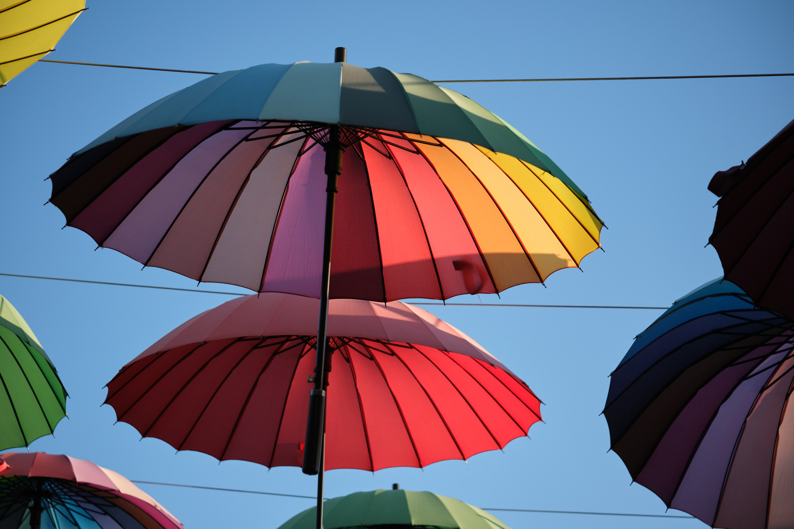 Разноцветные зонтики на фоне облаков