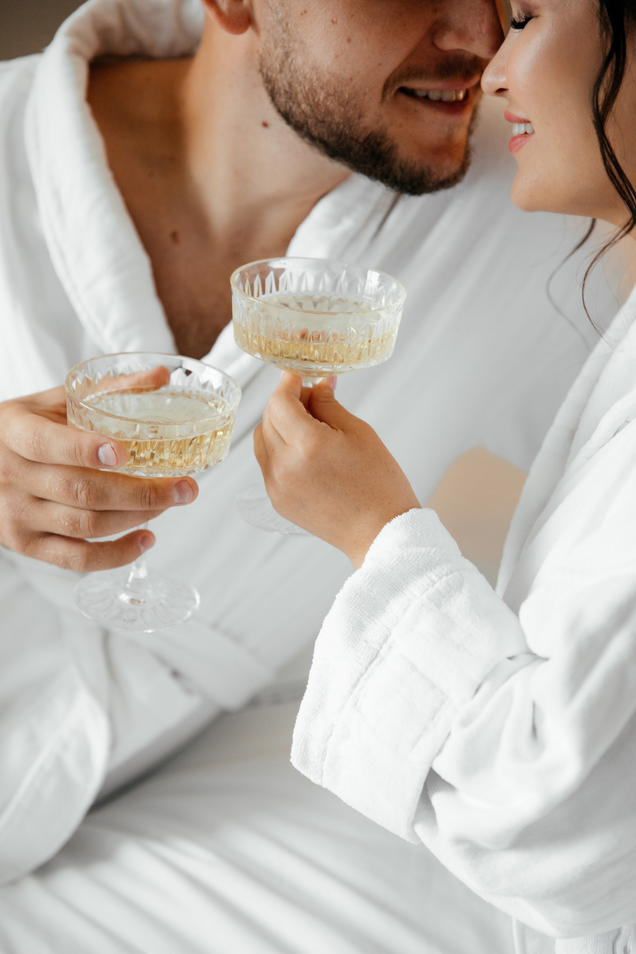 утро жениха с невестой в постели отеля с бокалом шампанского 