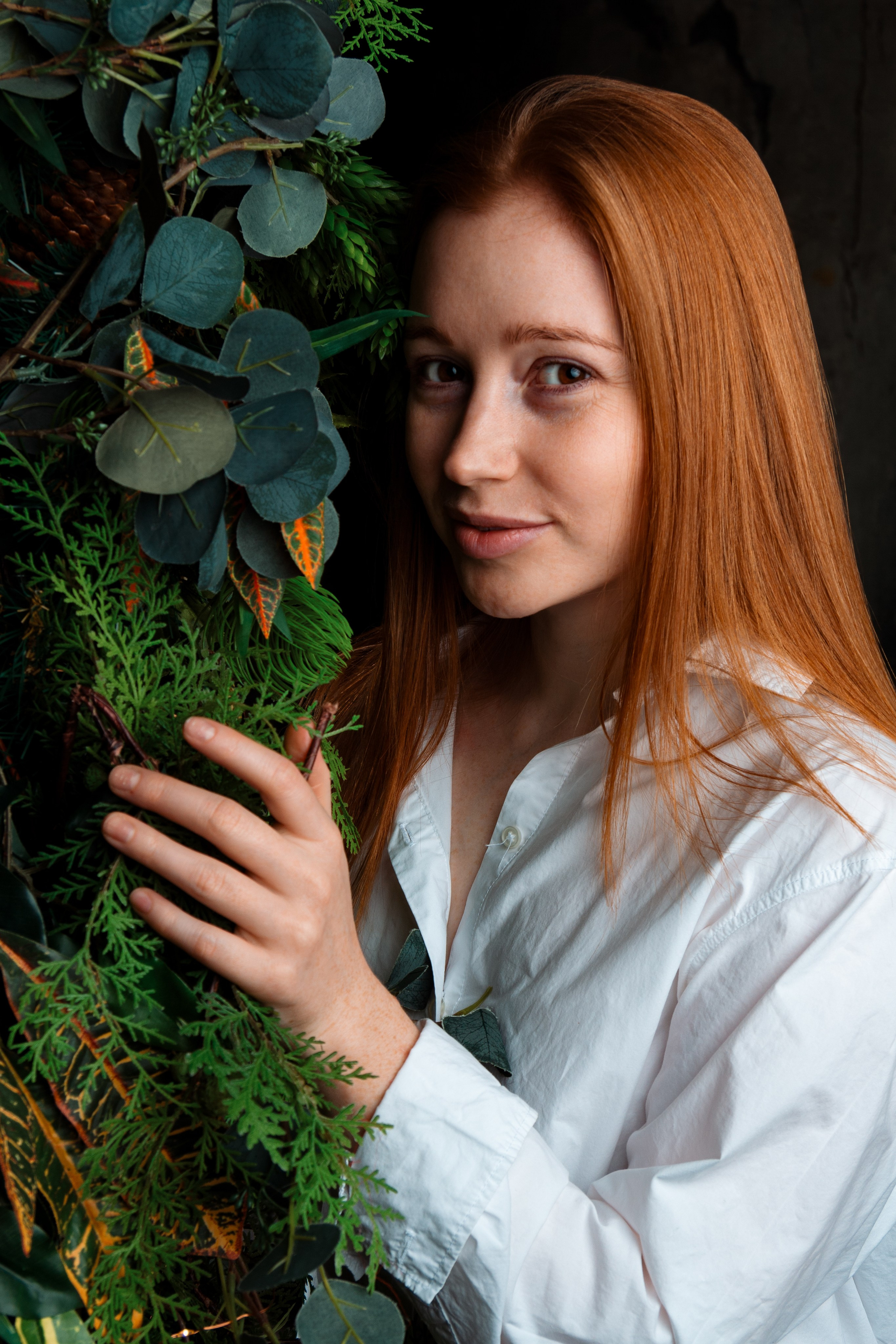 девушка прячется за листвой дерева 