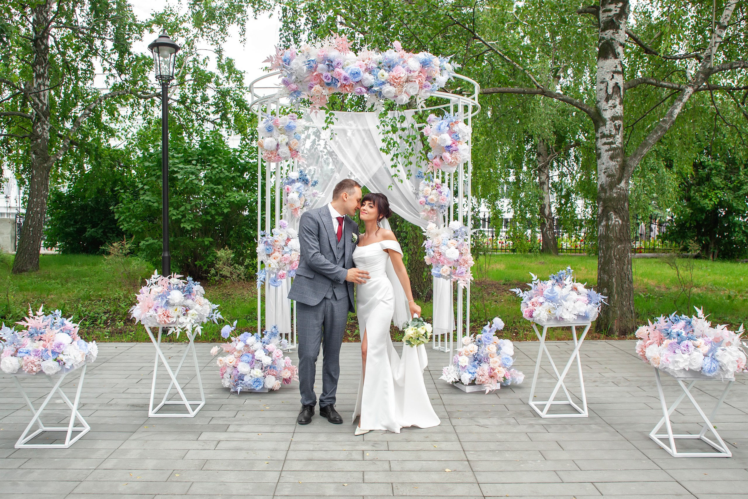 Жених и невеста стоят внутри праздничной арки