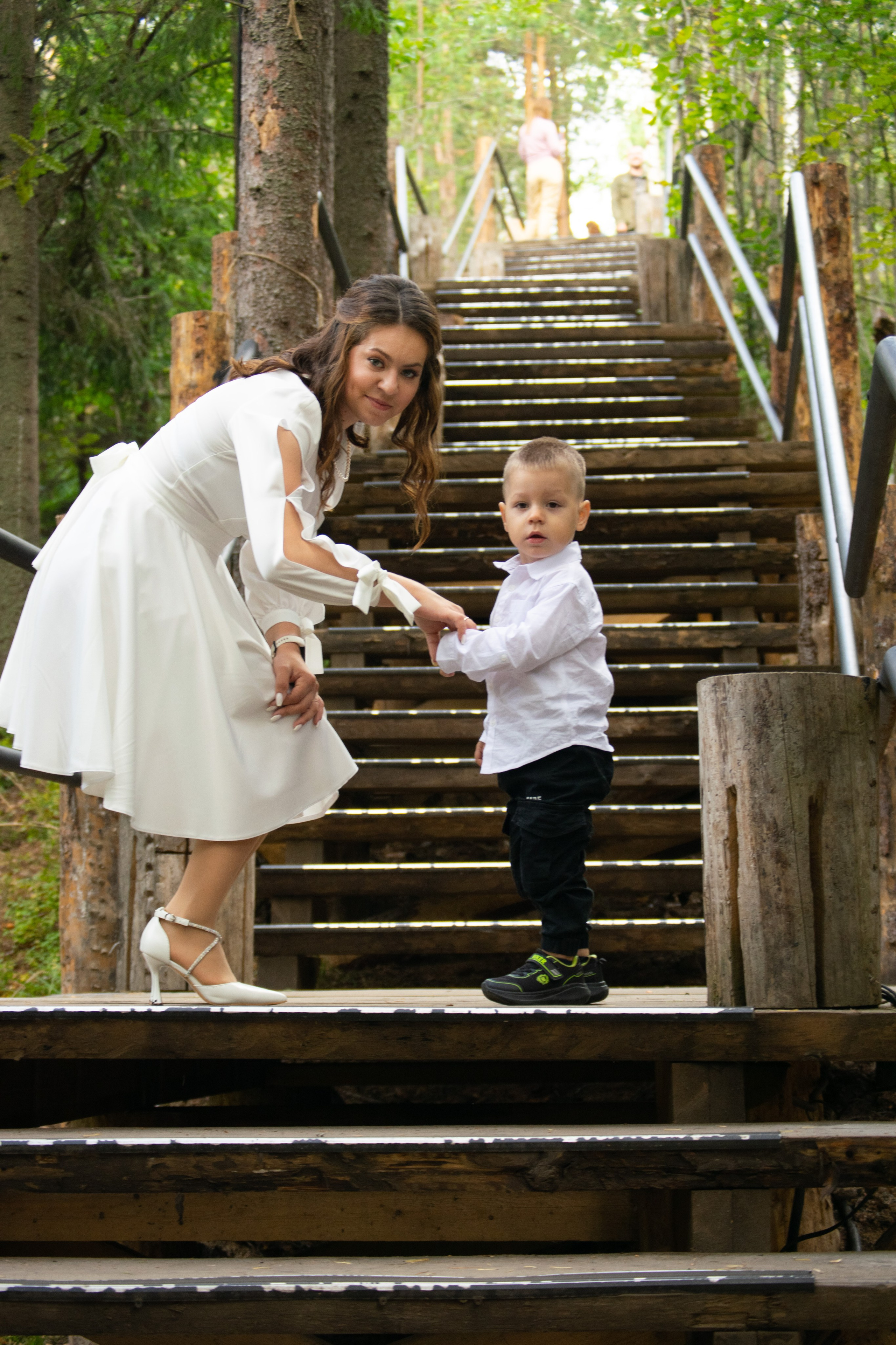 Свадебная фотосессия. Невеста в белом платье вместе со своим маленьким сыном поднимается по ступенькам. Гора Паасо, Сортавальский район.