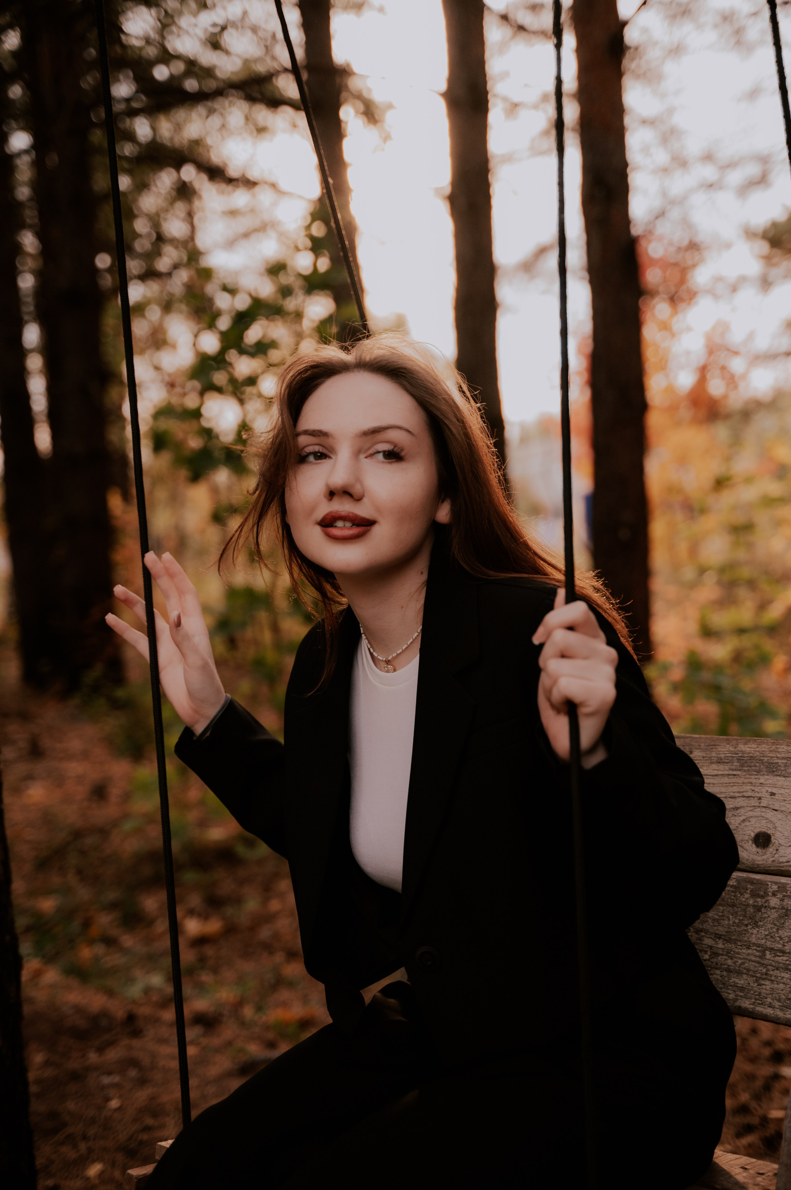 Красивая девушка катается на качелях на закате в лесу