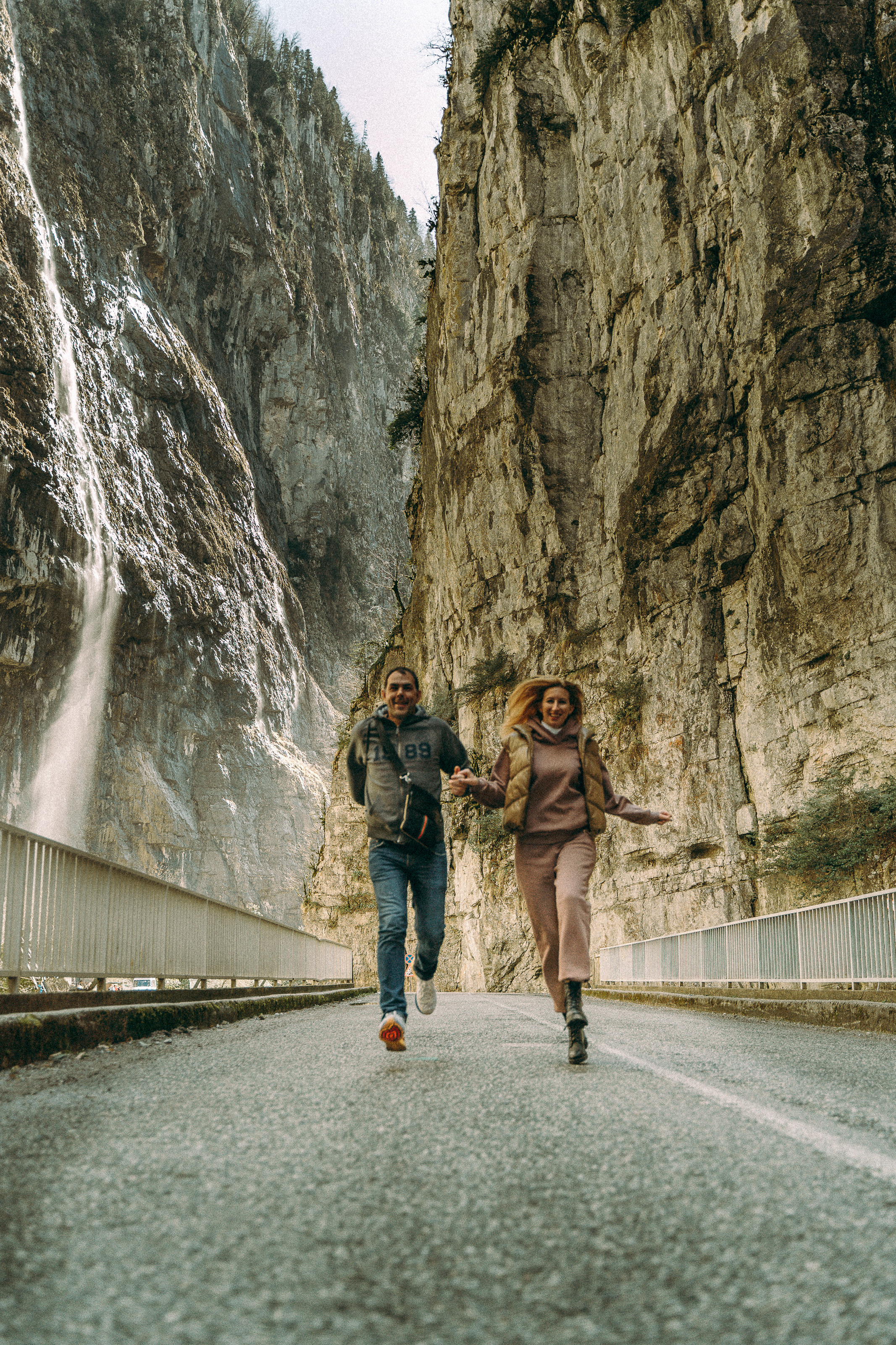 Девушка и парень бегут между скалами в Юпшарском каньоне