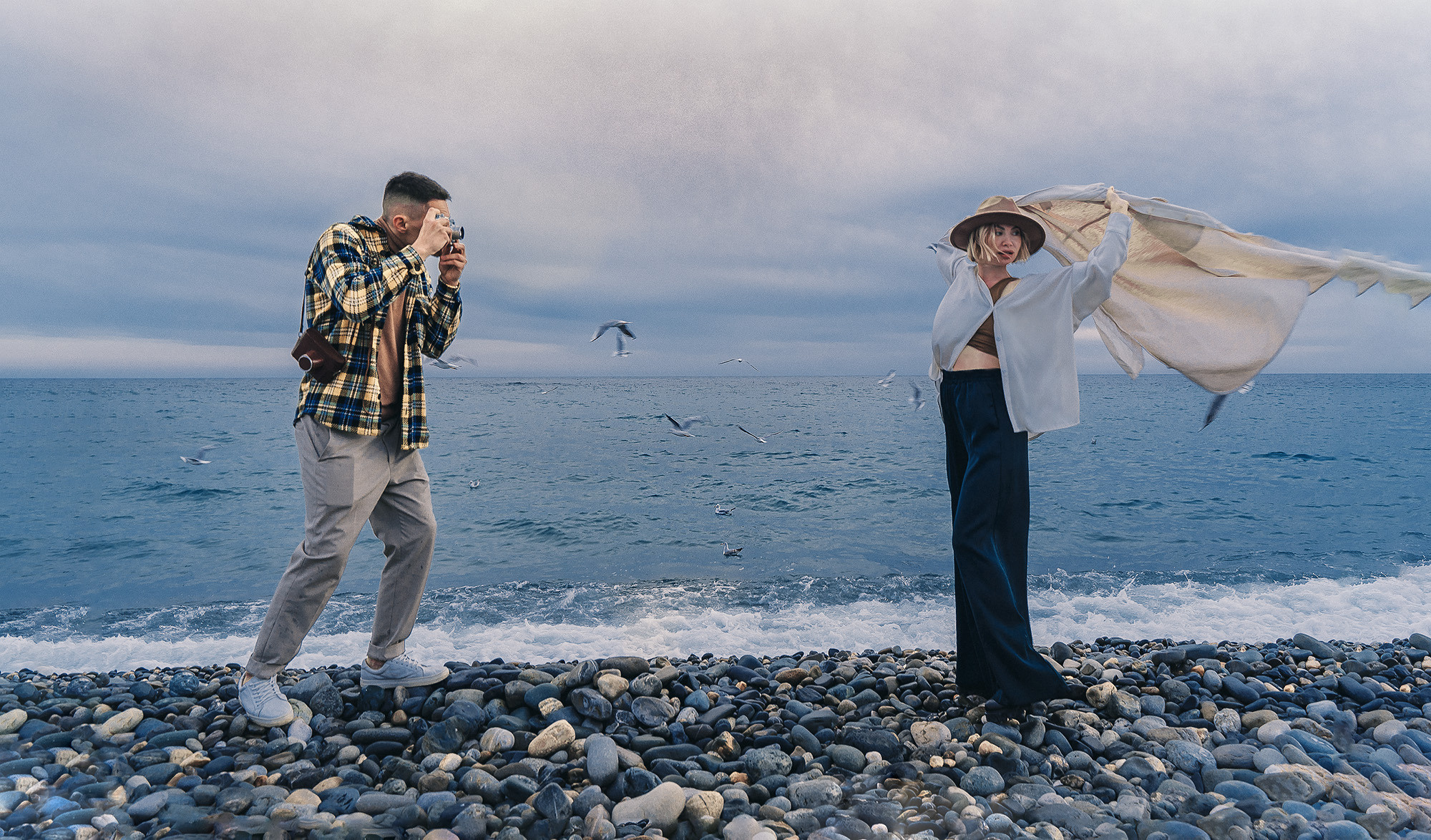 Парень фотографирует девушку в шляпе на море