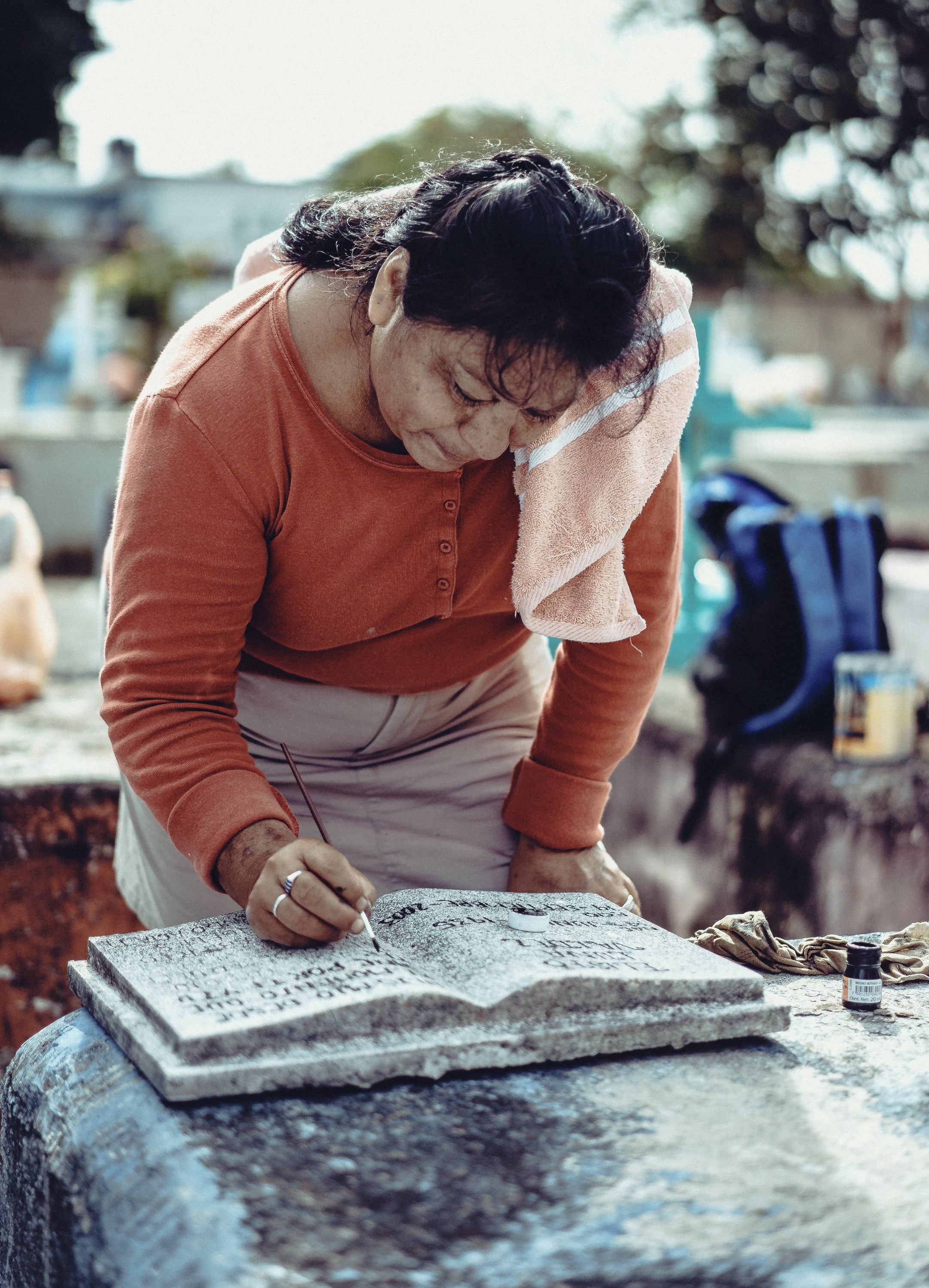 Женщина обновляет надписи на могиле.
