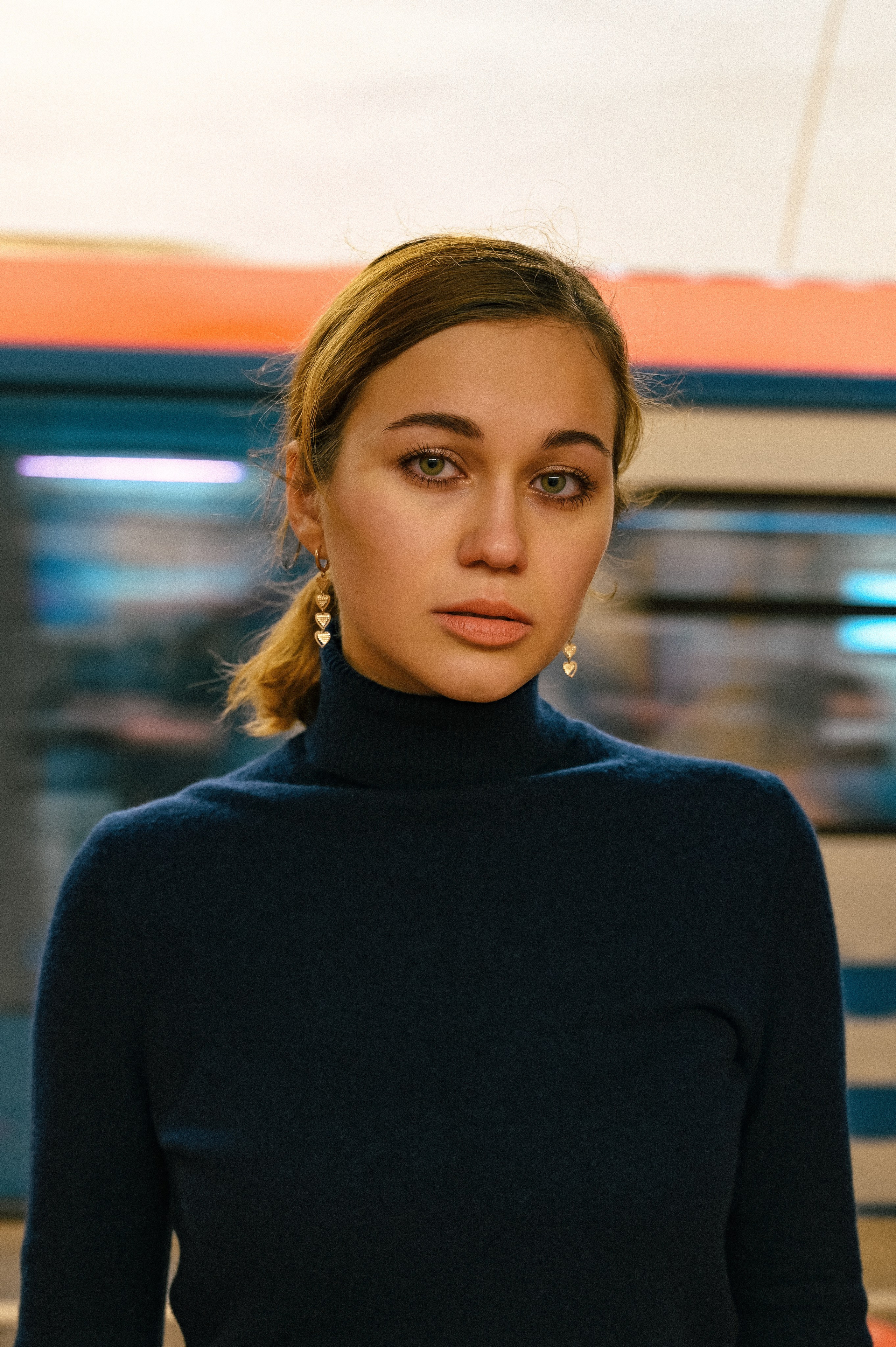Портрет девушки с элегантными серьгами и тёмным свитером, запечатлённый в московском метро с эффектом движения.