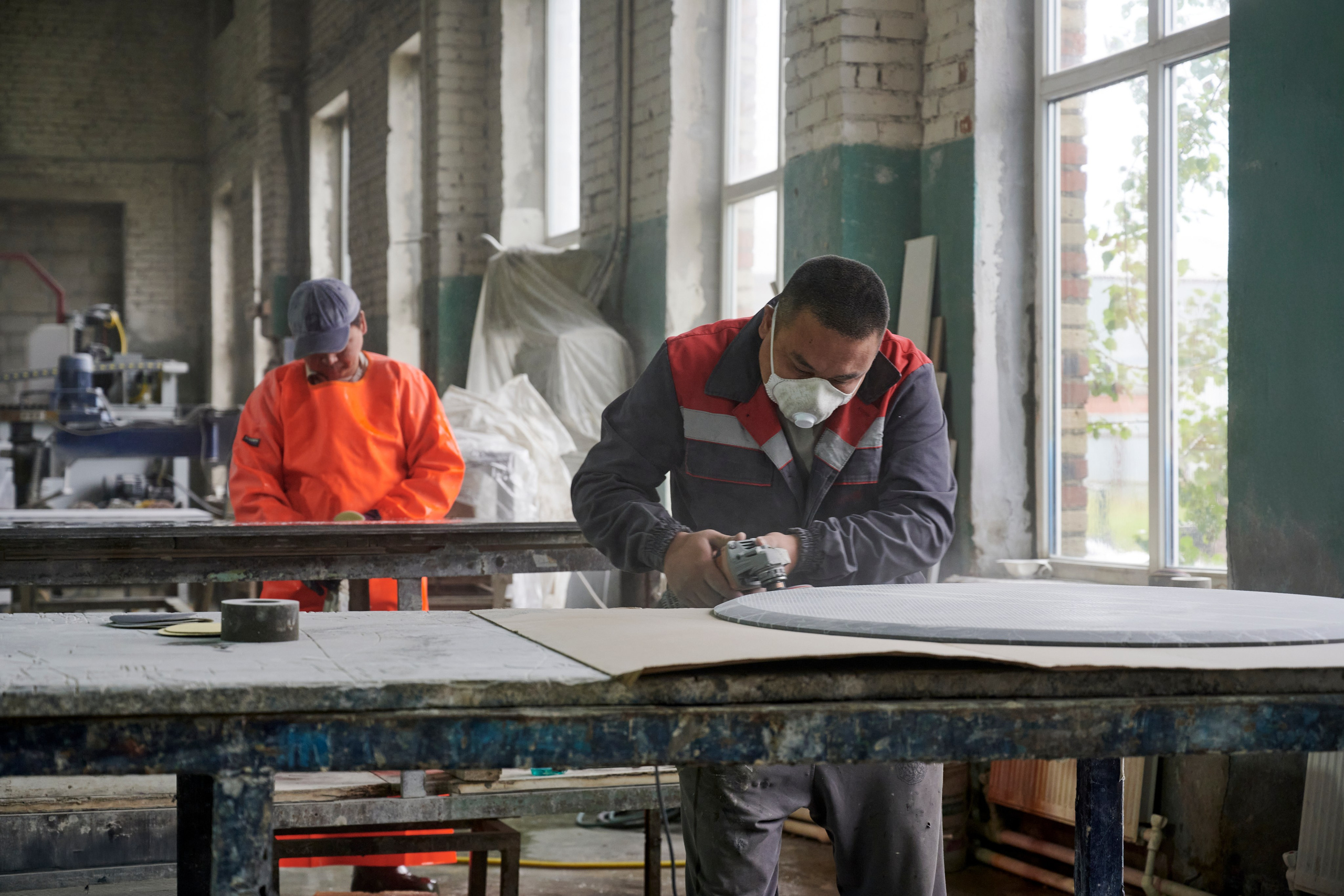 Рабочие обрабатывают каменную плиту на производственном столе