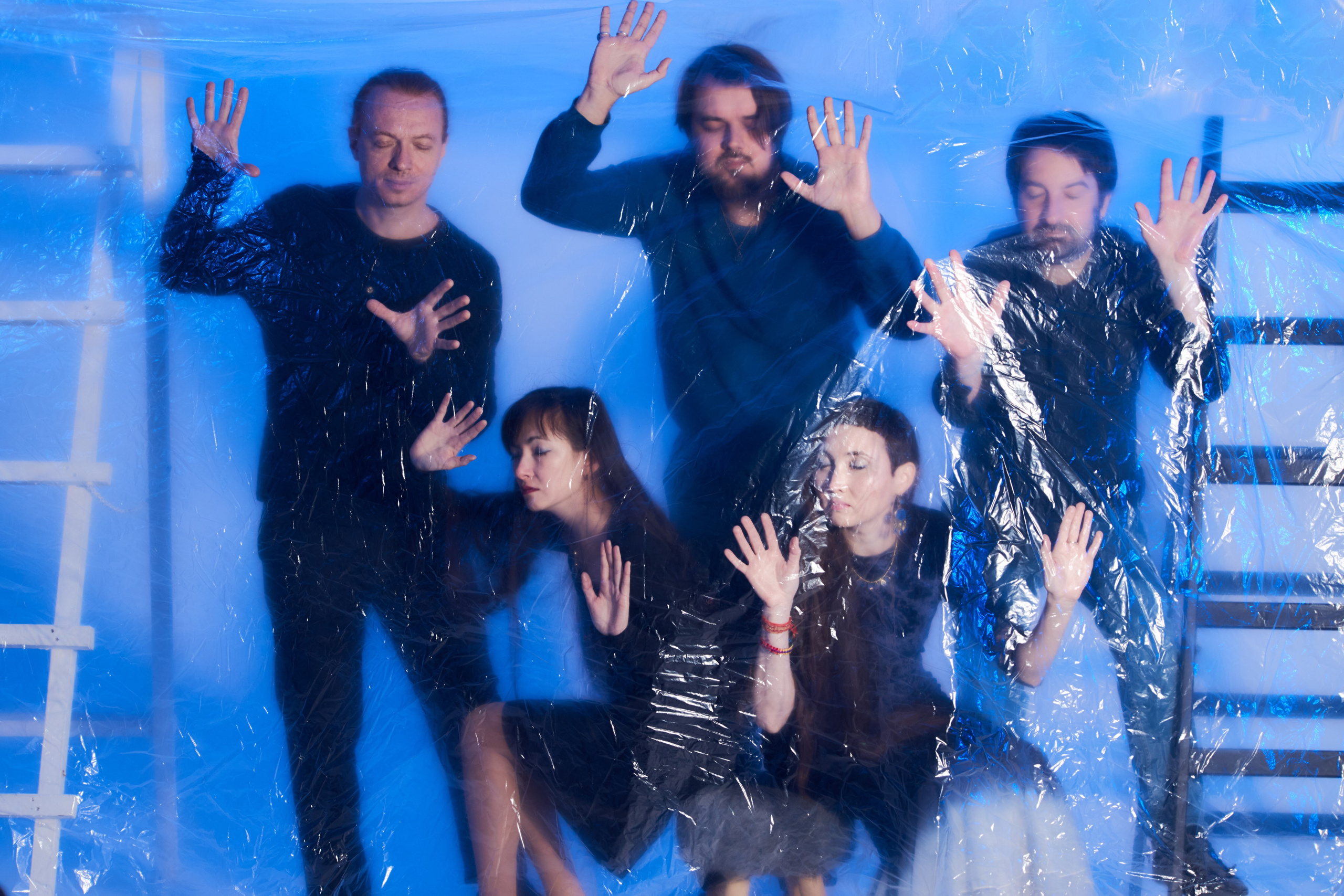 Групповое фото пяти человек с лентами и цветным светом под прозрачной полиэтиленовой плёнкой