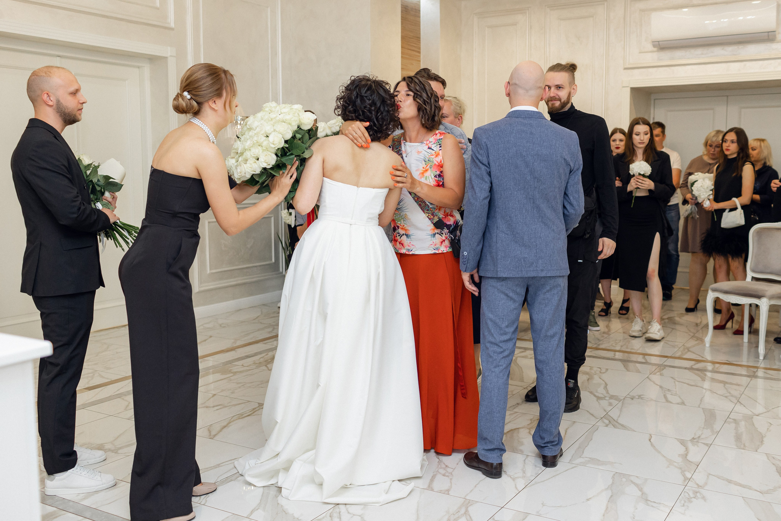 трогательный мент: гости обнимают и поздравляю молодоженов после регистрации брака 