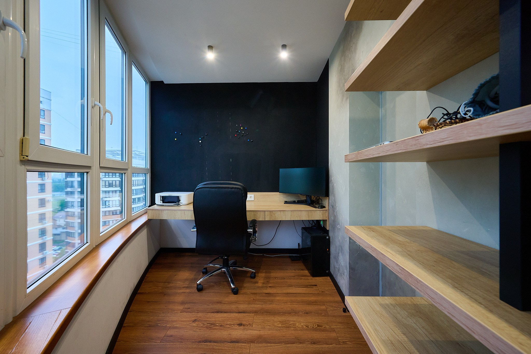 на балконе деревянный стол с черным стулом и деревянным шкафчиком 