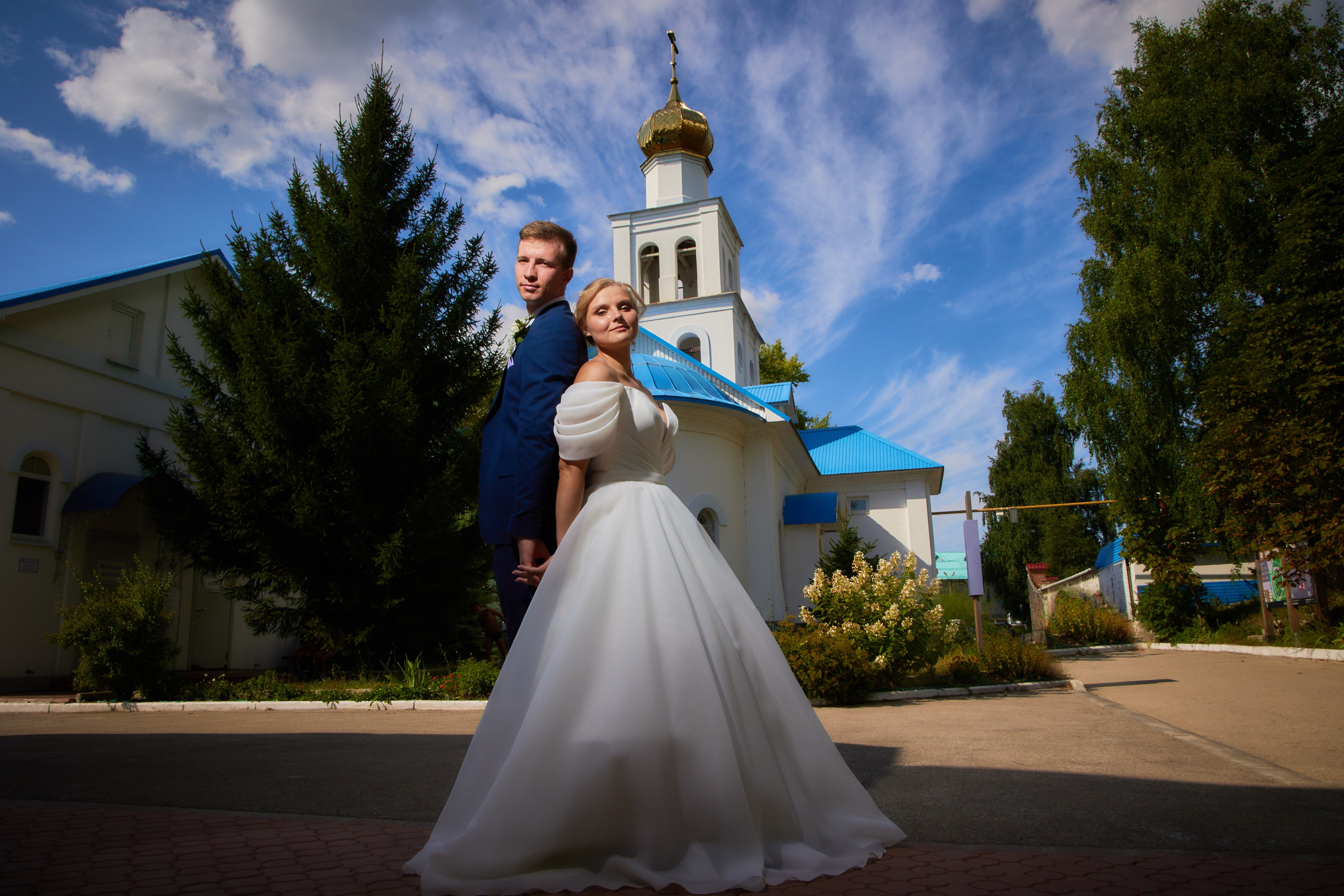 свадебная фотография у церкви с красивыми облаками