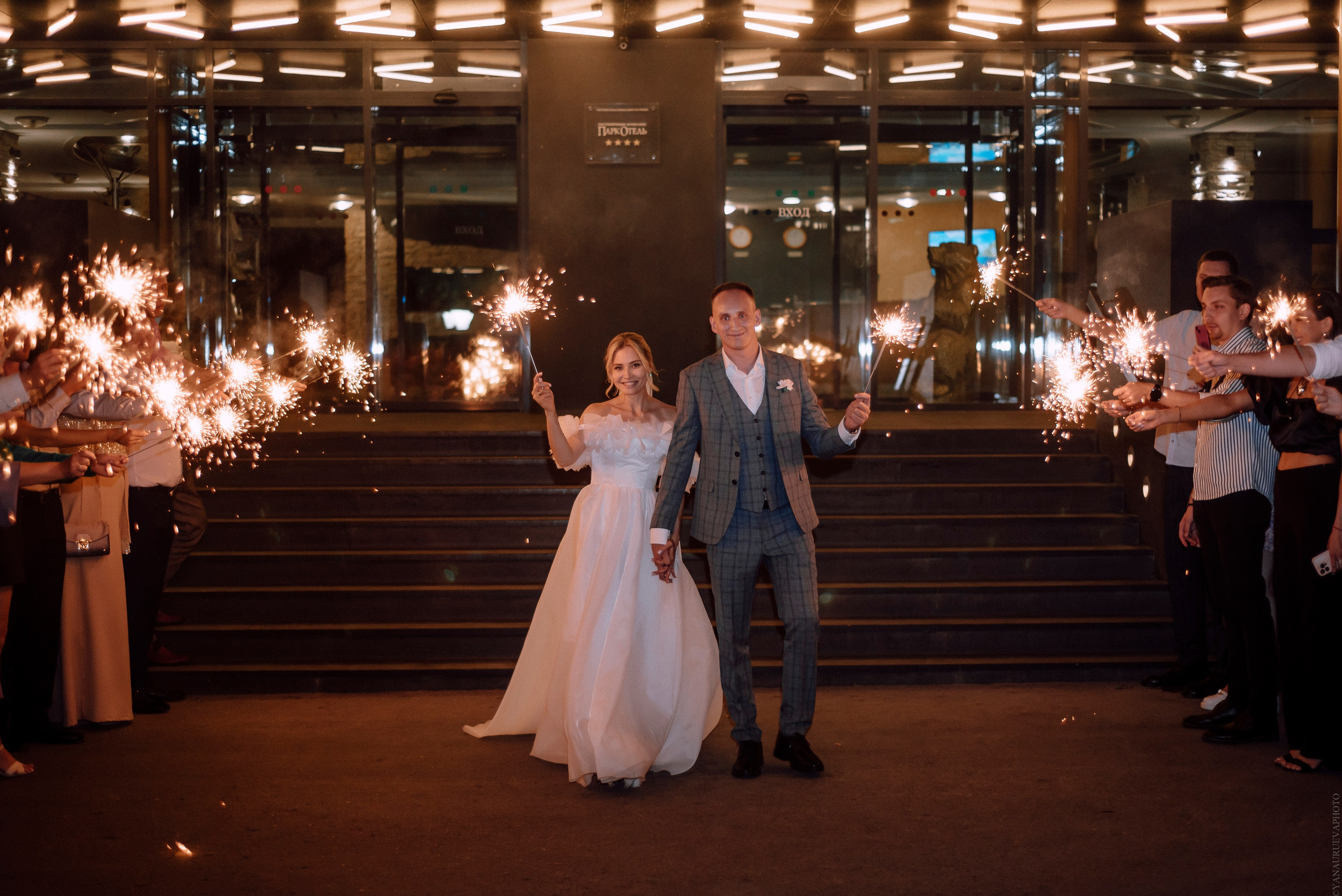 Жених и невеста держат бенгальские огни и идут 