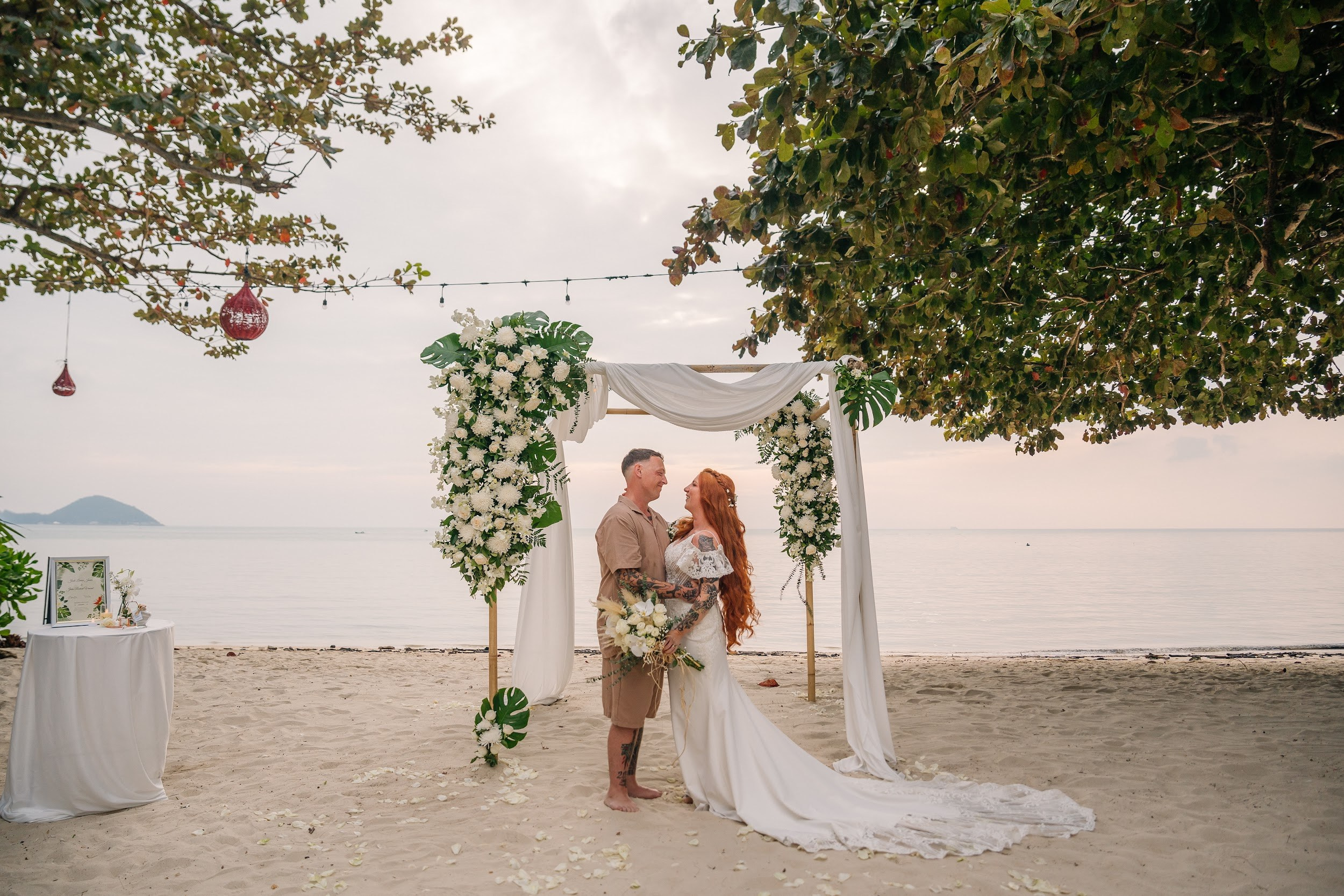 Wedding ceremony on a tropical beach in Koh Samui, Thailand with floral arch and turquoise sea in the background