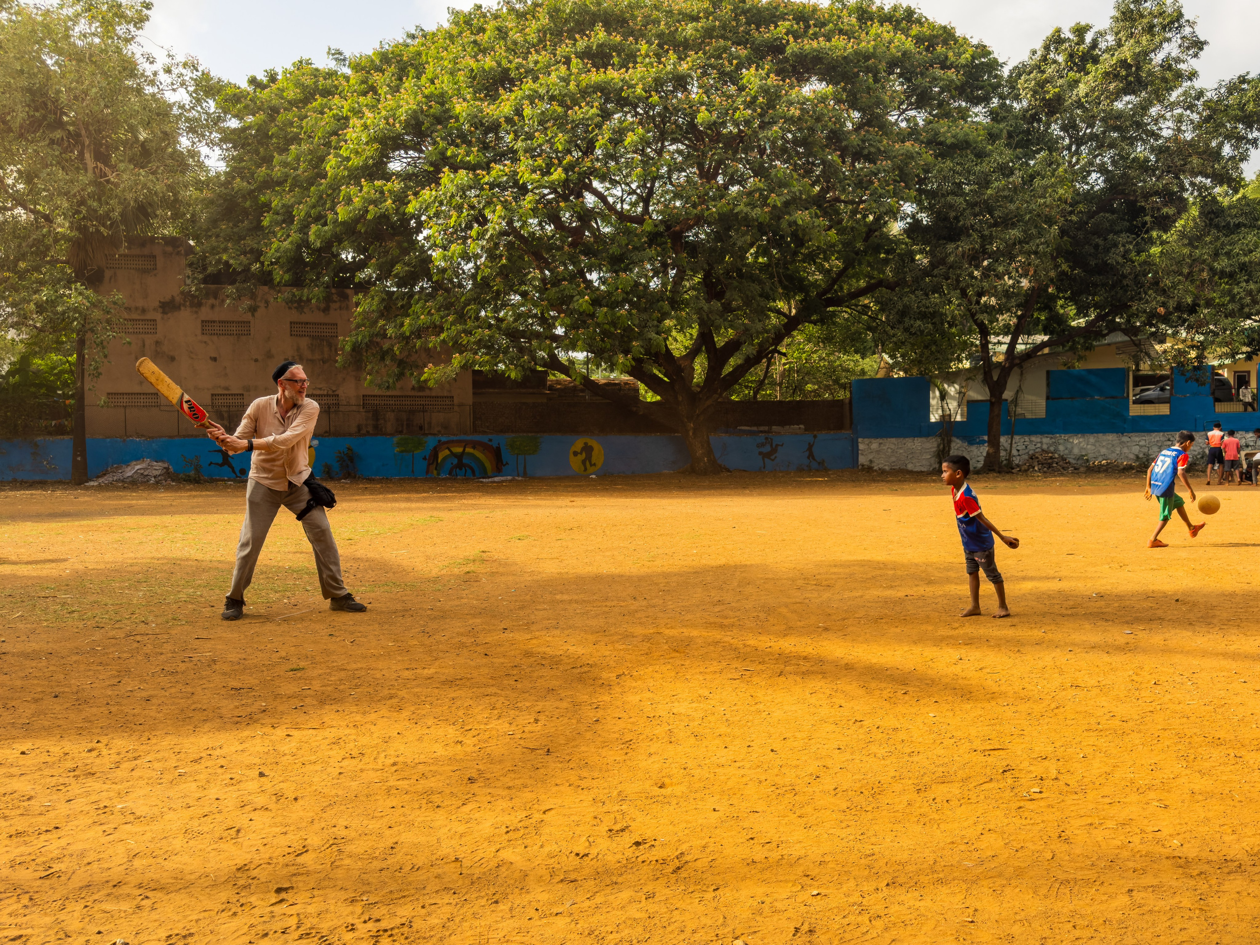 Дети играют в спортивные игры на песчаном поле с деревьями на фоне