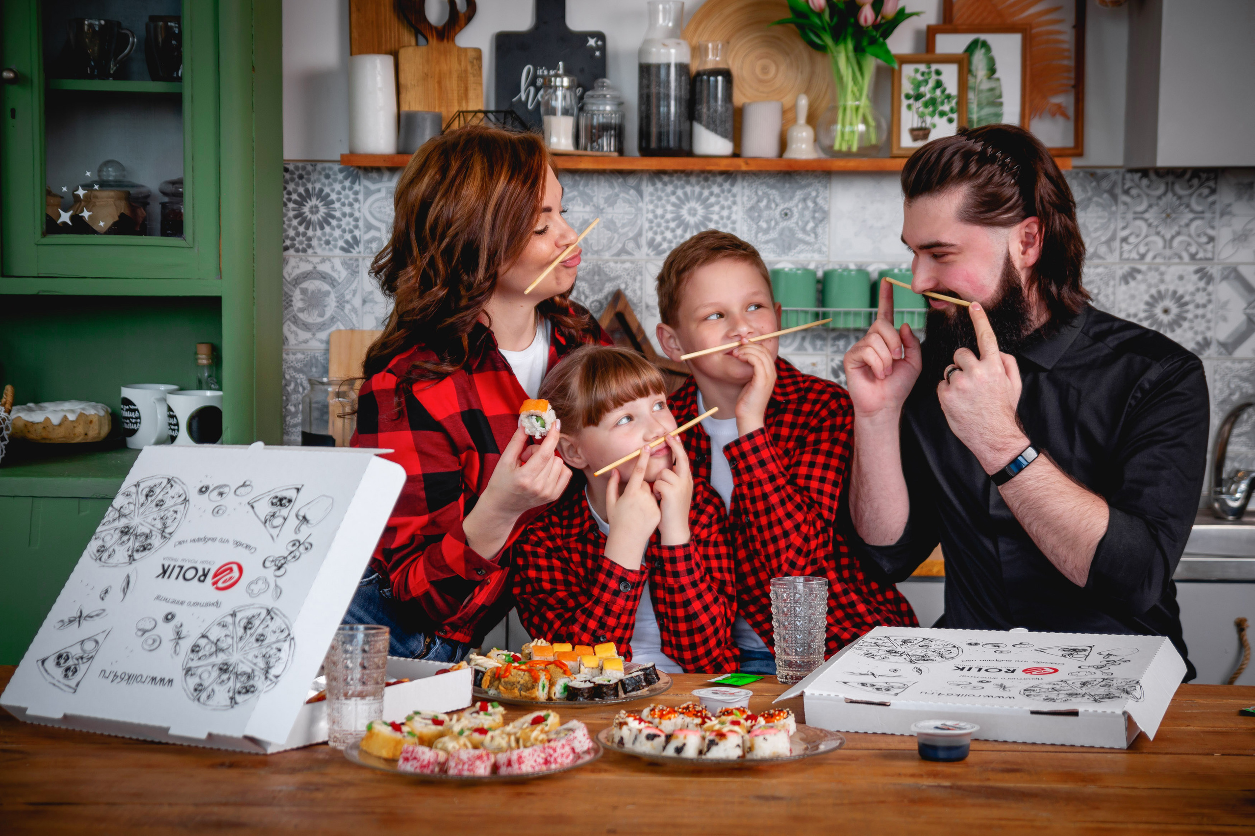 Счастливая семья, папа мама и маленькие брат с сестрой за обеденным столом кушают пиццу с роллами из Rolik (Rolik64)