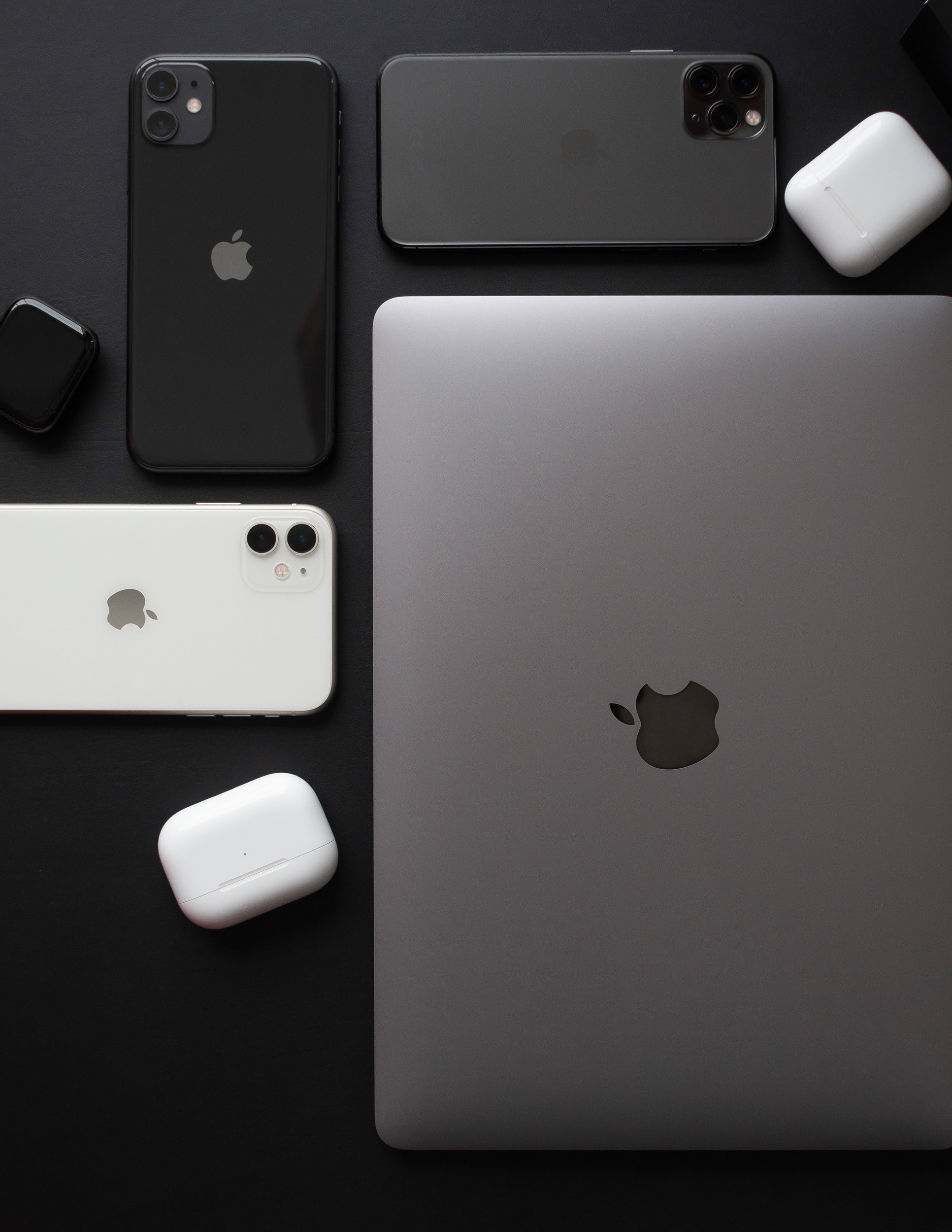 эпл техника, электроника, Macbook, iPhone, Airpods Pro лежат на темном столе