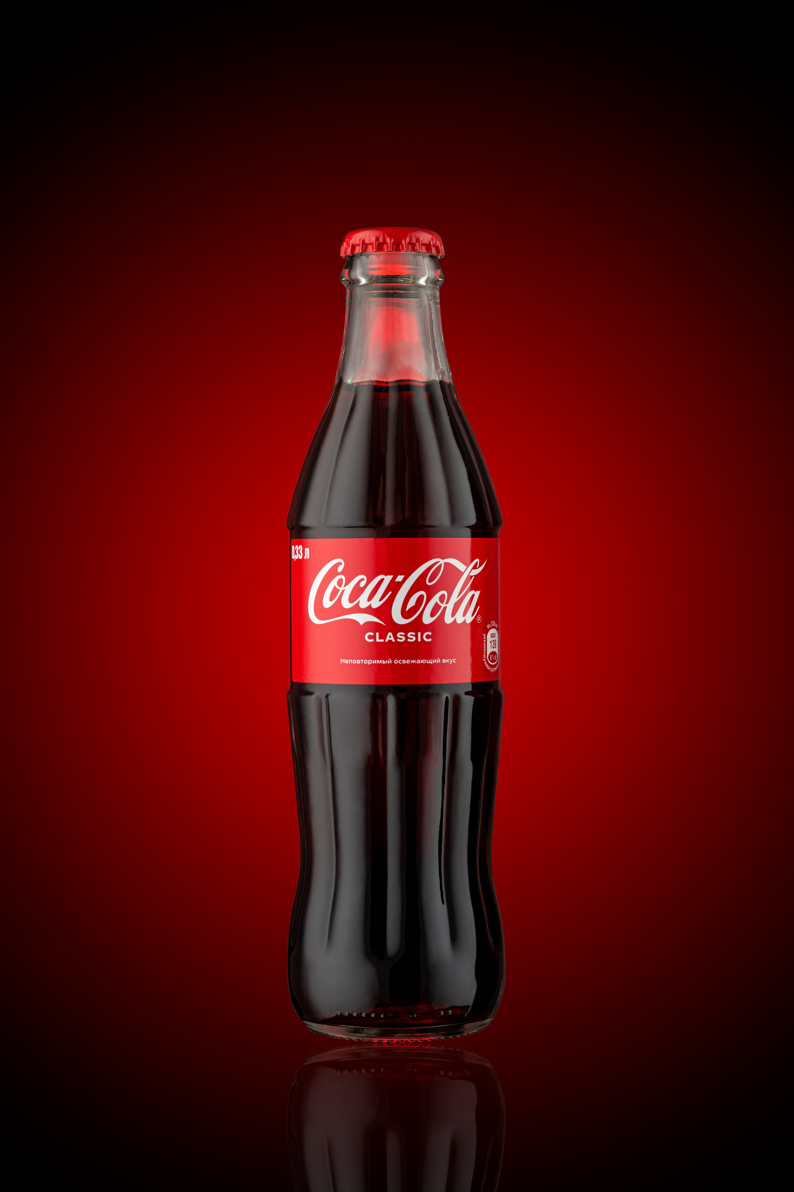 Стеклянная бутылка coca cola на красном градиентном фоне