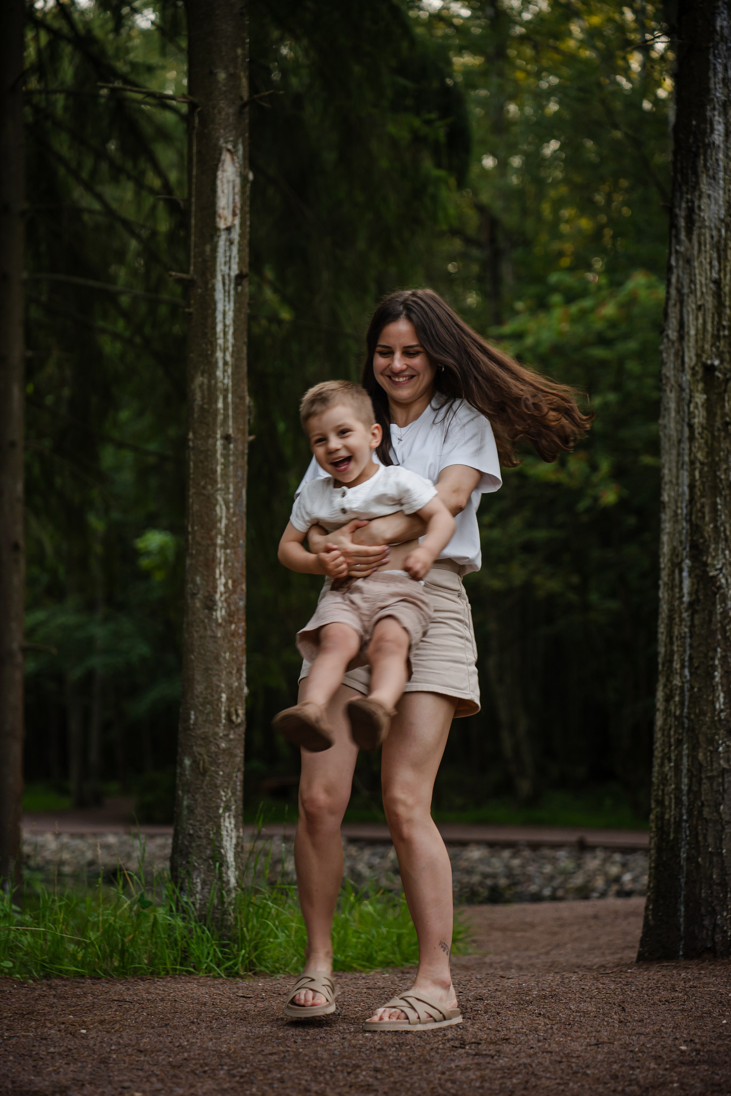 мама кружит ребенка в парке