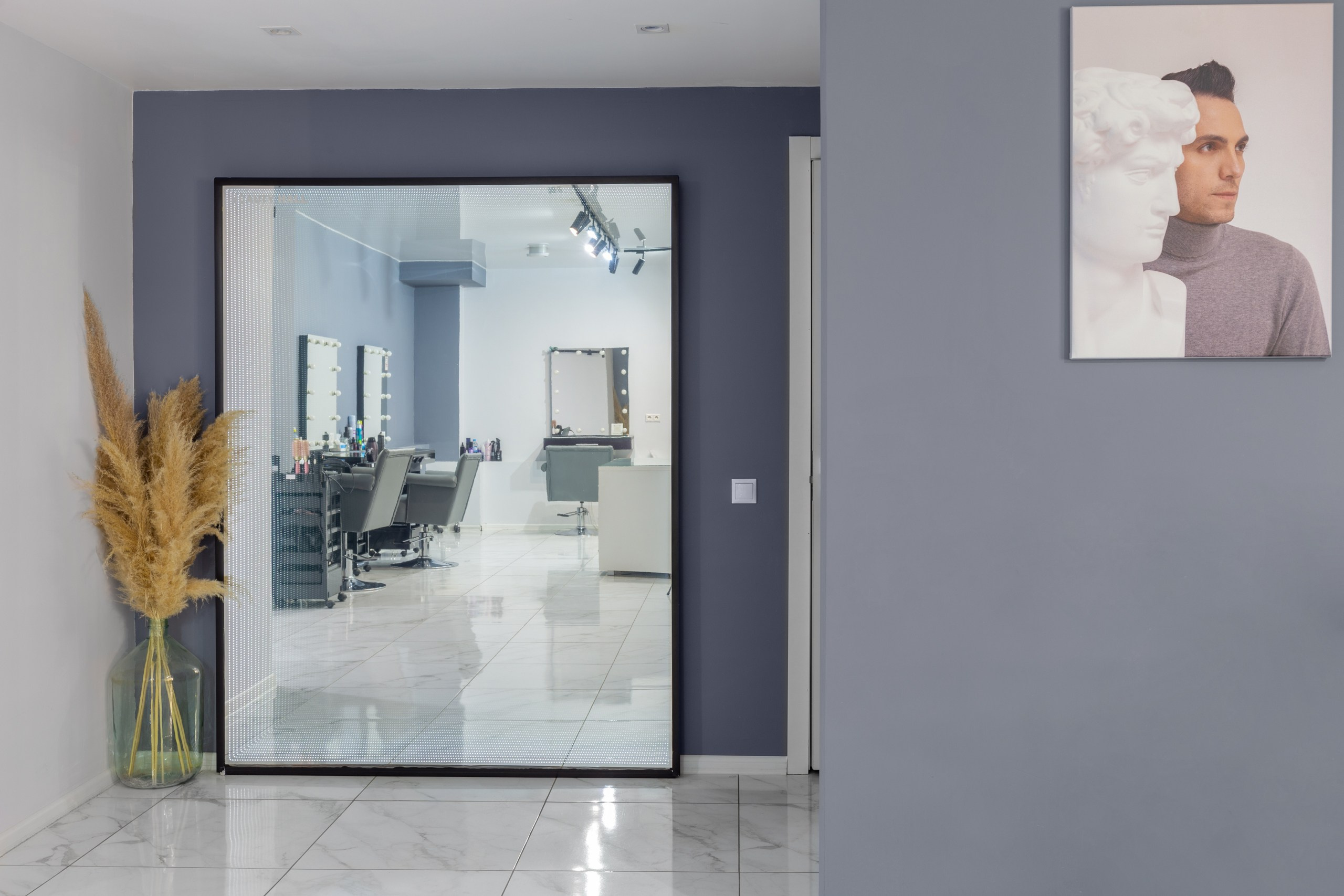 Зеркало в интерьере салона красоты. Большое зеркало. Отражение место парикмахера. Фото картина на серой стене.