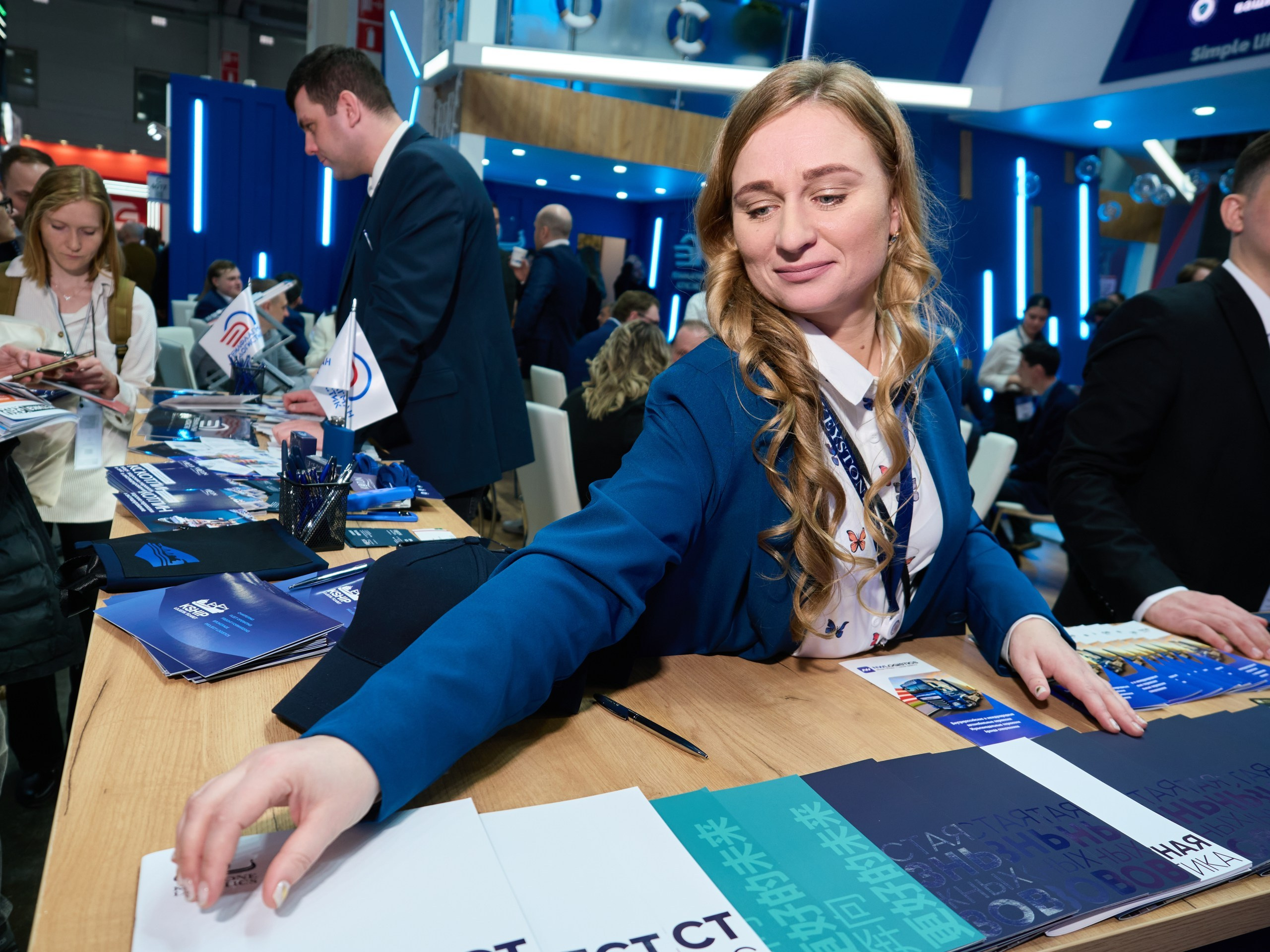 Девушка поправляет рекламу на выставке в Москве портрет
