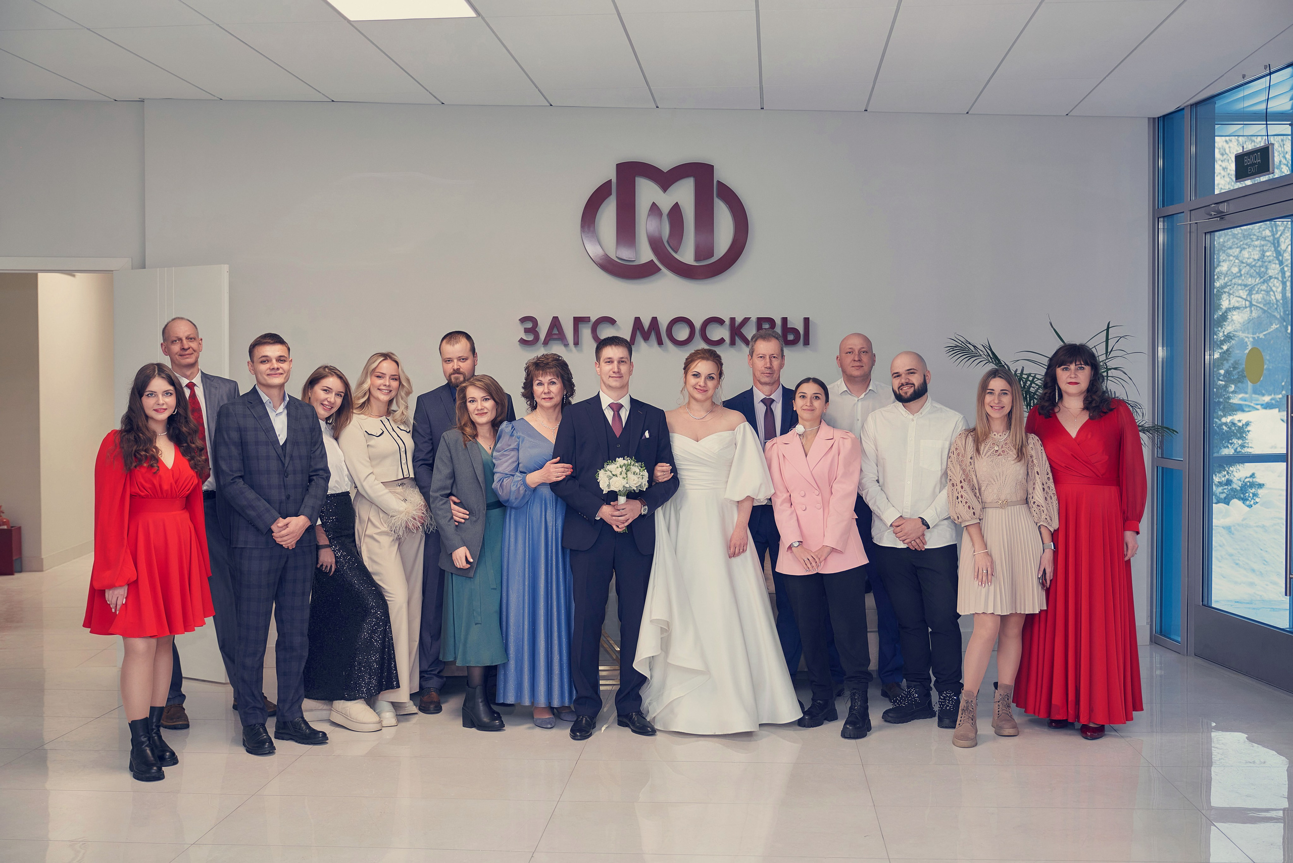 общая фотография с гостями в Шипиловском ЗАГС на фоне эмблемы 