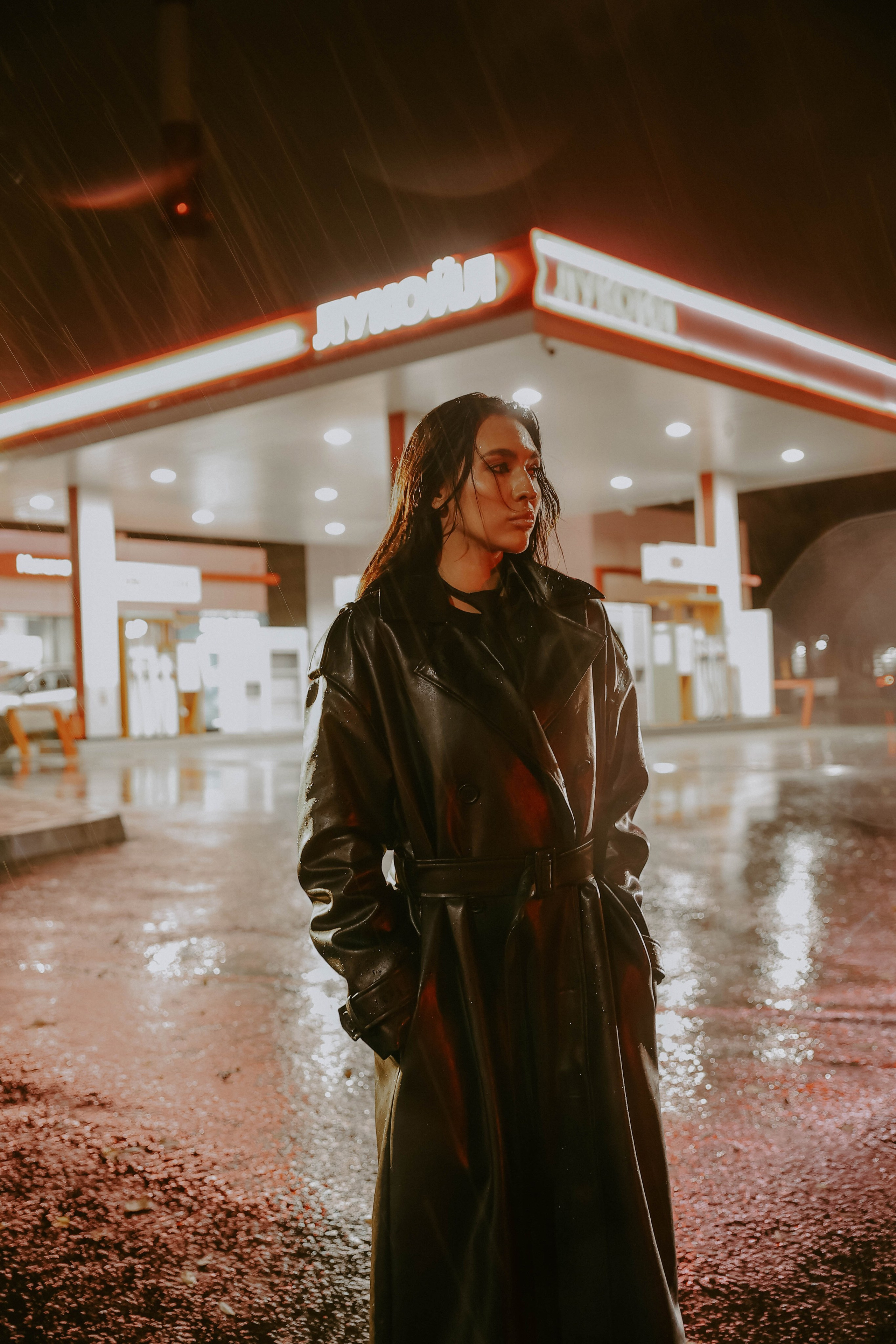 Фотосессия девушки в кожаном плаще ночью на заправке под дождем