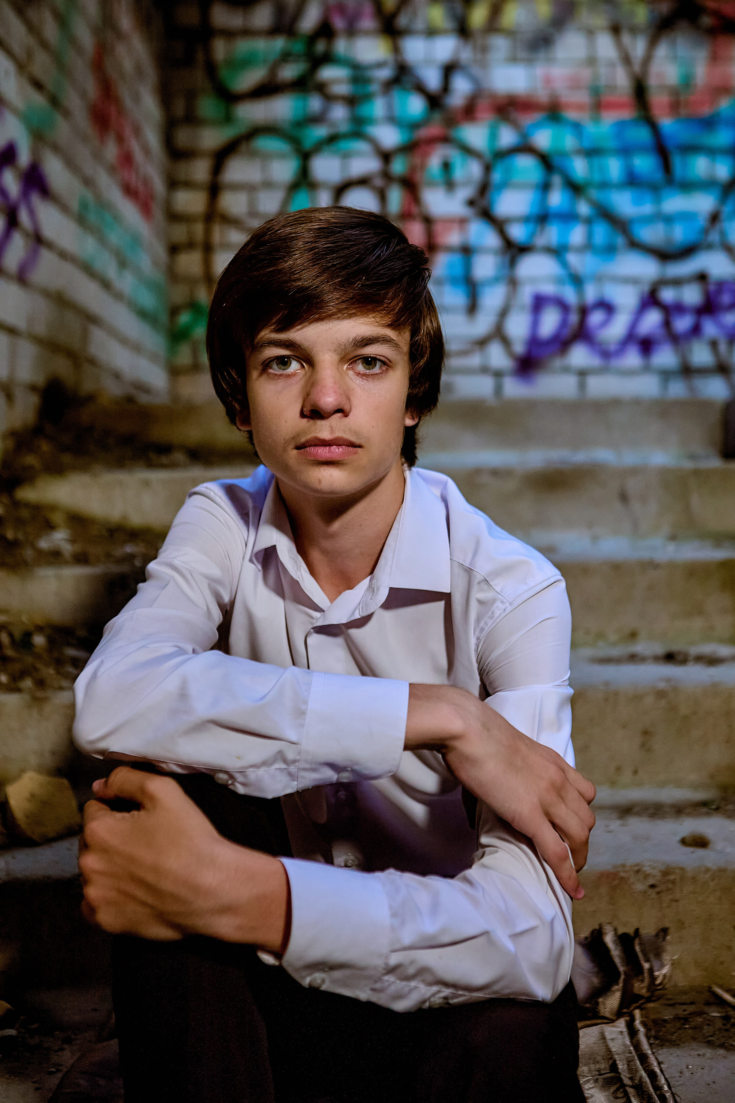 Парень сидит на лестнице в заброшенном здании, молодежный портрет