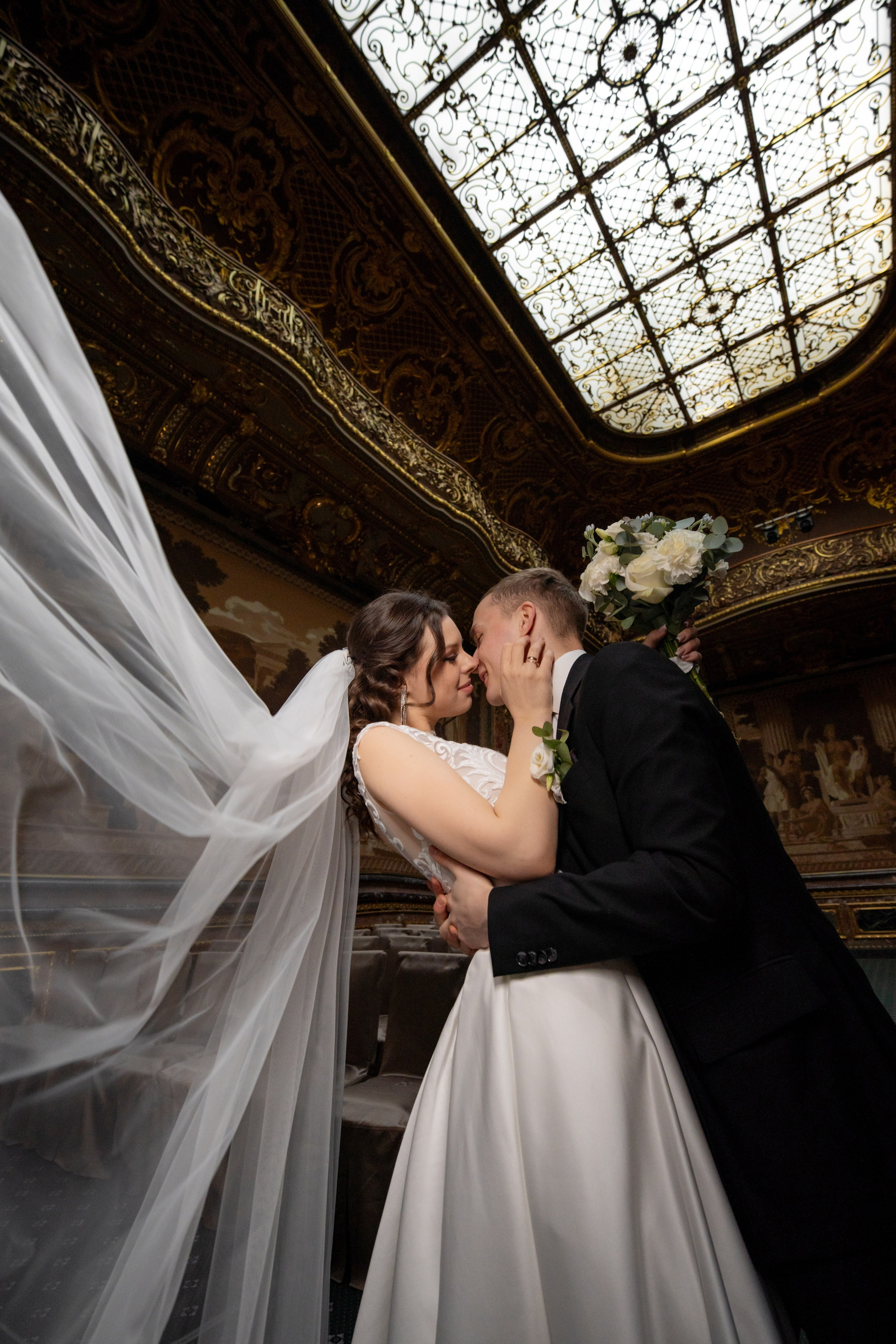 Свадебная фотосессия в Санкт-Петербурге в Особняке Половцева или Дом Архитектора. жених красиво целует невесту с прогибом и фата летит в зале театра.
