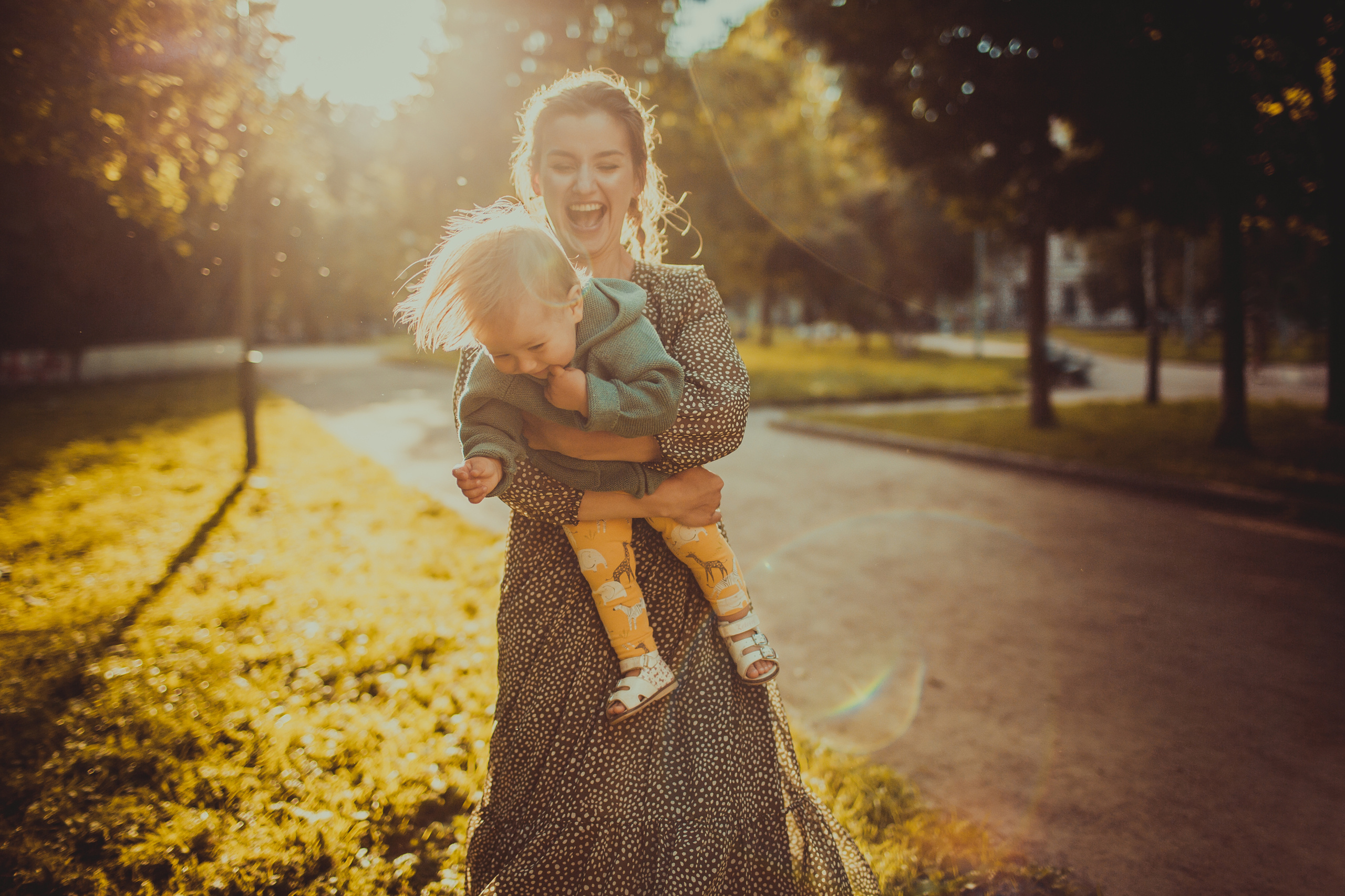 смеющаяся мама с маленькой дочкой в контровом солнечном свете