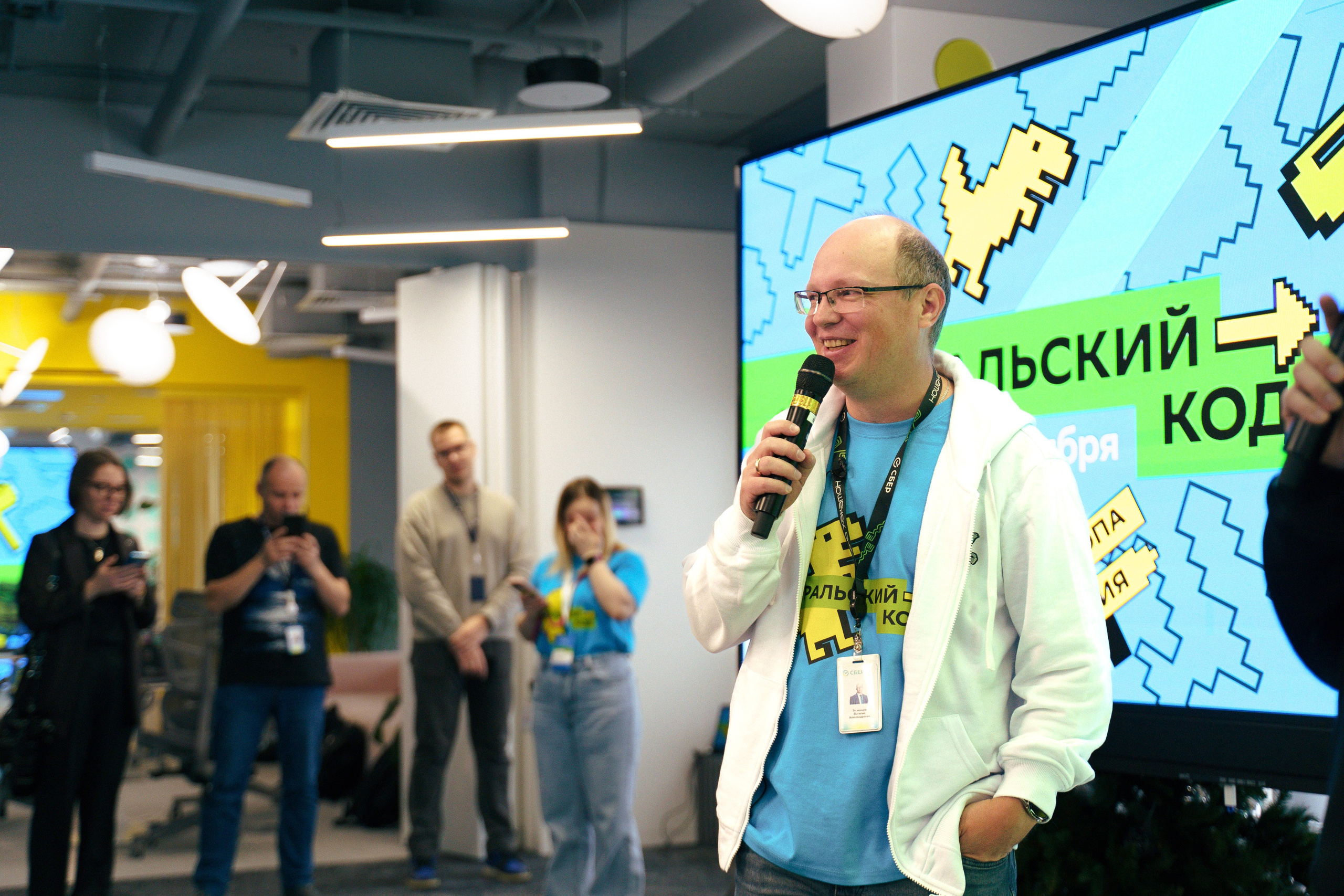 Организатор говорит в микрофон перед командой разработчиков