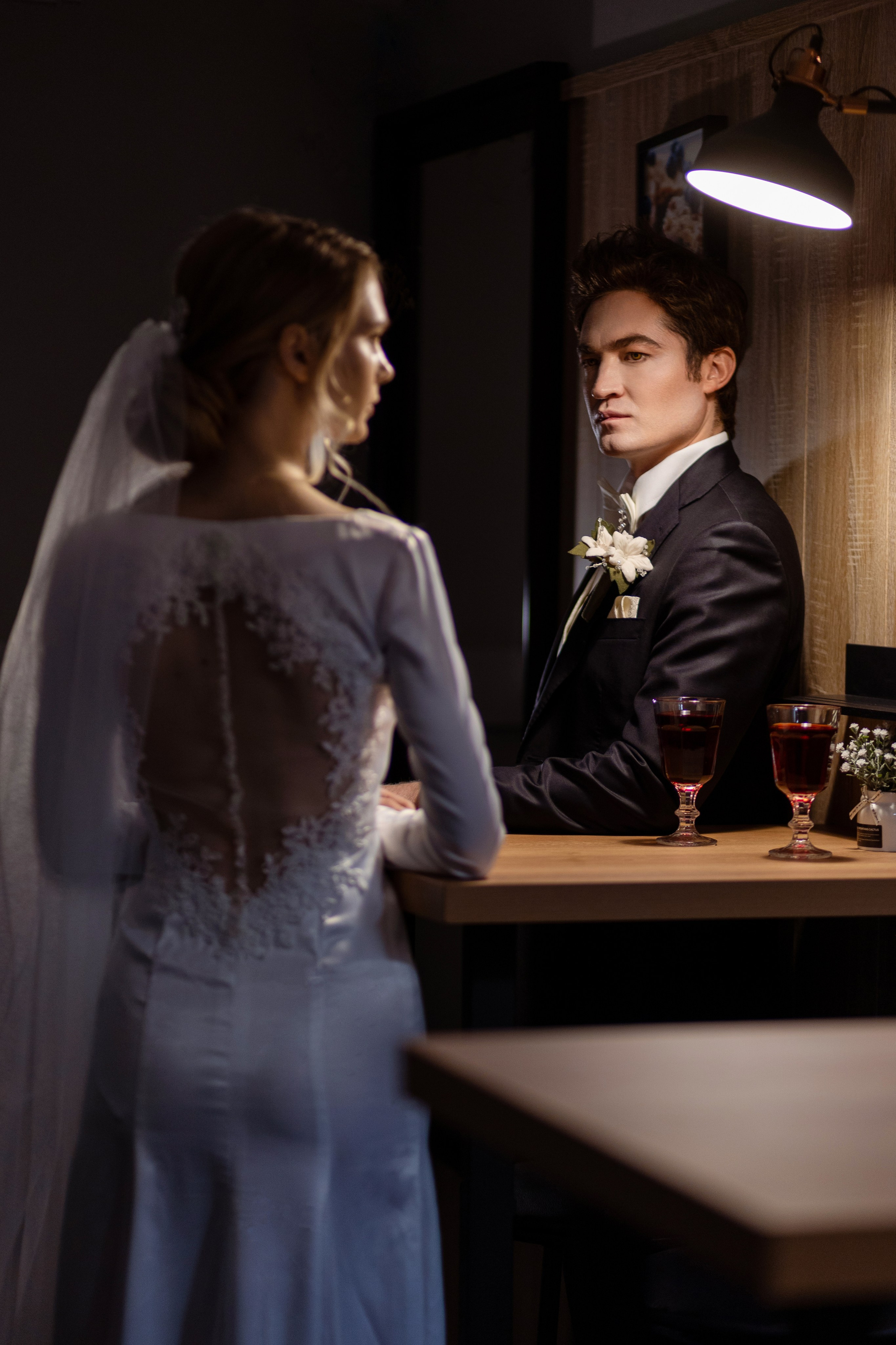 Невеста стоит спиной у стола, за которым стоит жених.