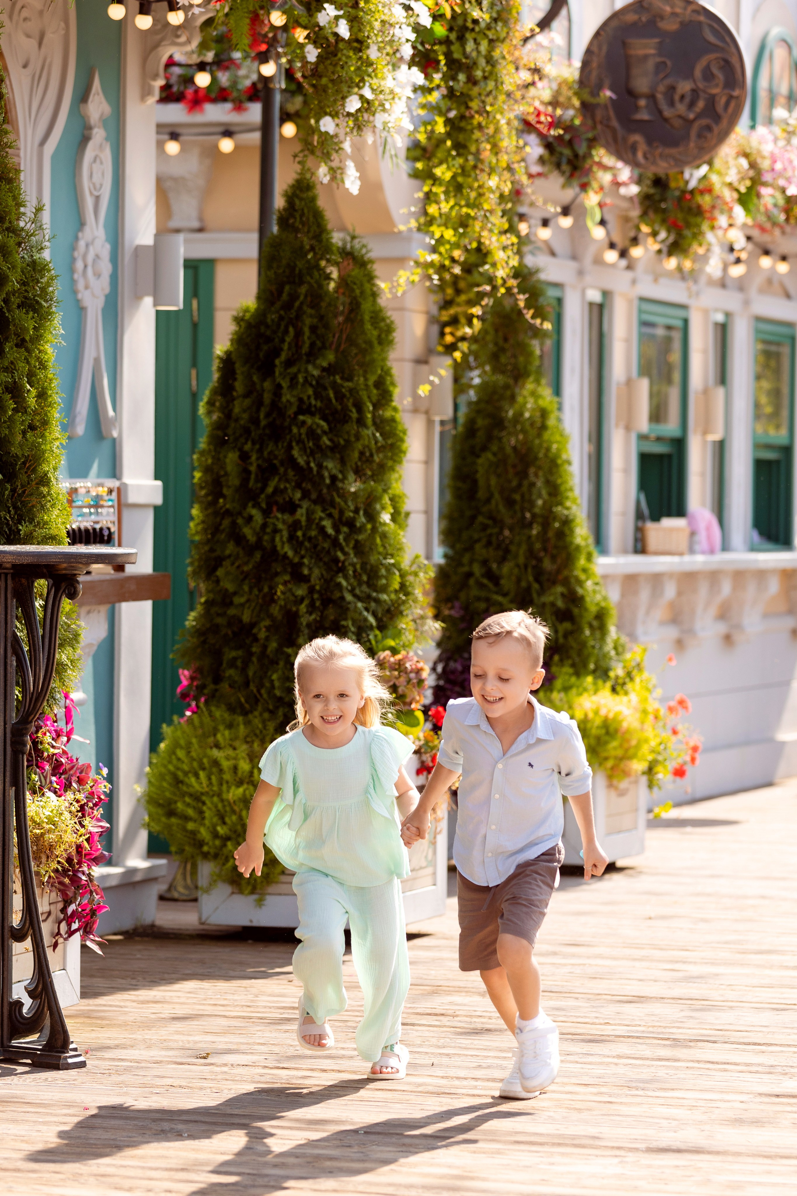 Девочка и мальчик бегут по парку взявшись за руки