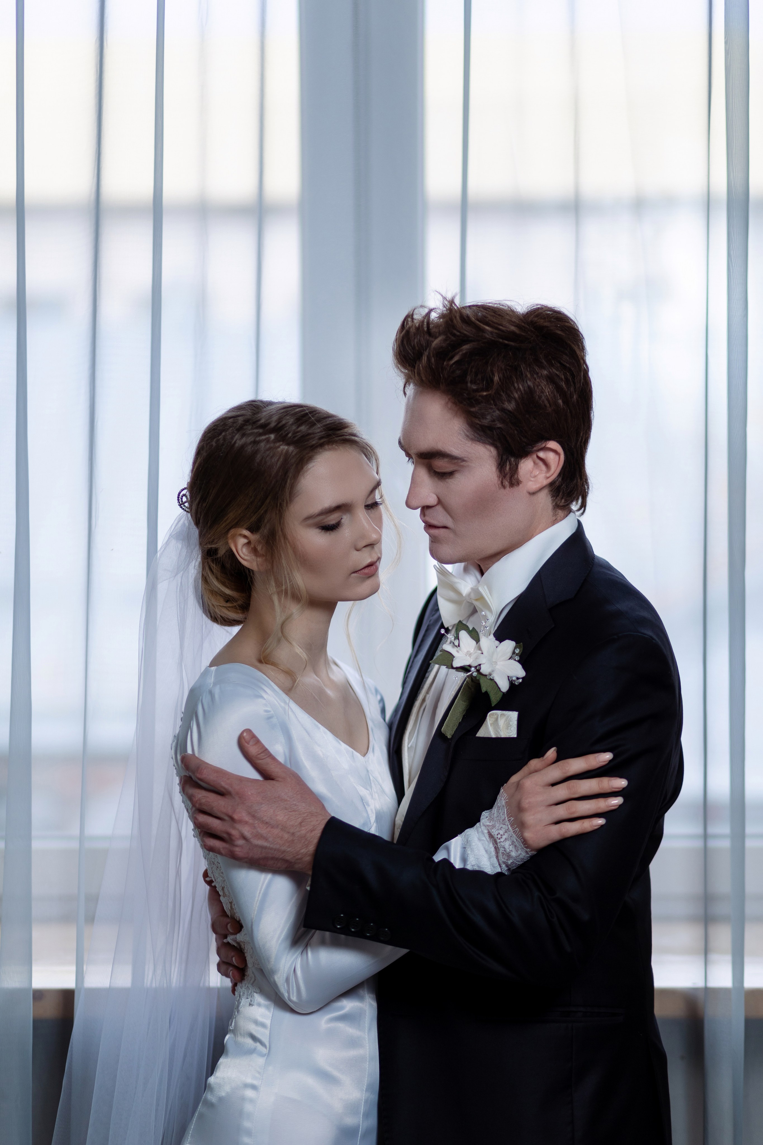 Жених и невеста на светлом фоне окна.