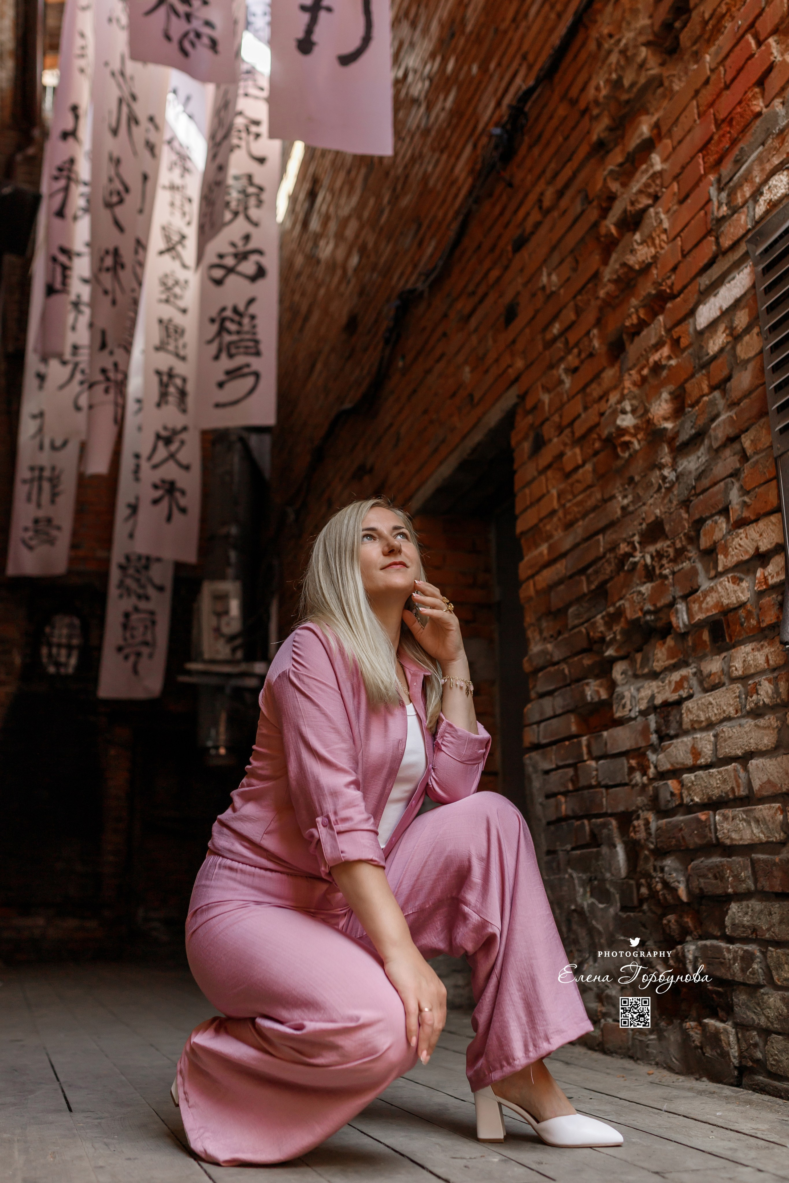 девушка сидит на корточках с интересной локации, ракурс снизу