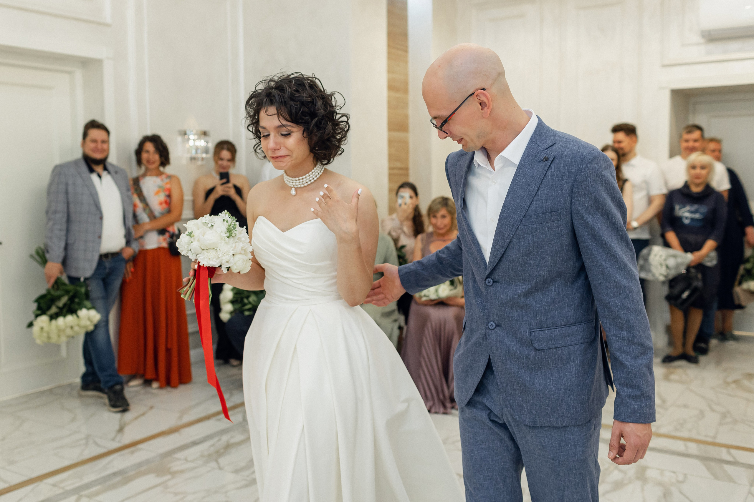 Искренние эмоции в Центральном ЗАГСе Архангельска: невеста в атласном платье плачет от счастья во время росписи на фоне мраморных стен фото от Клещинова Алексея