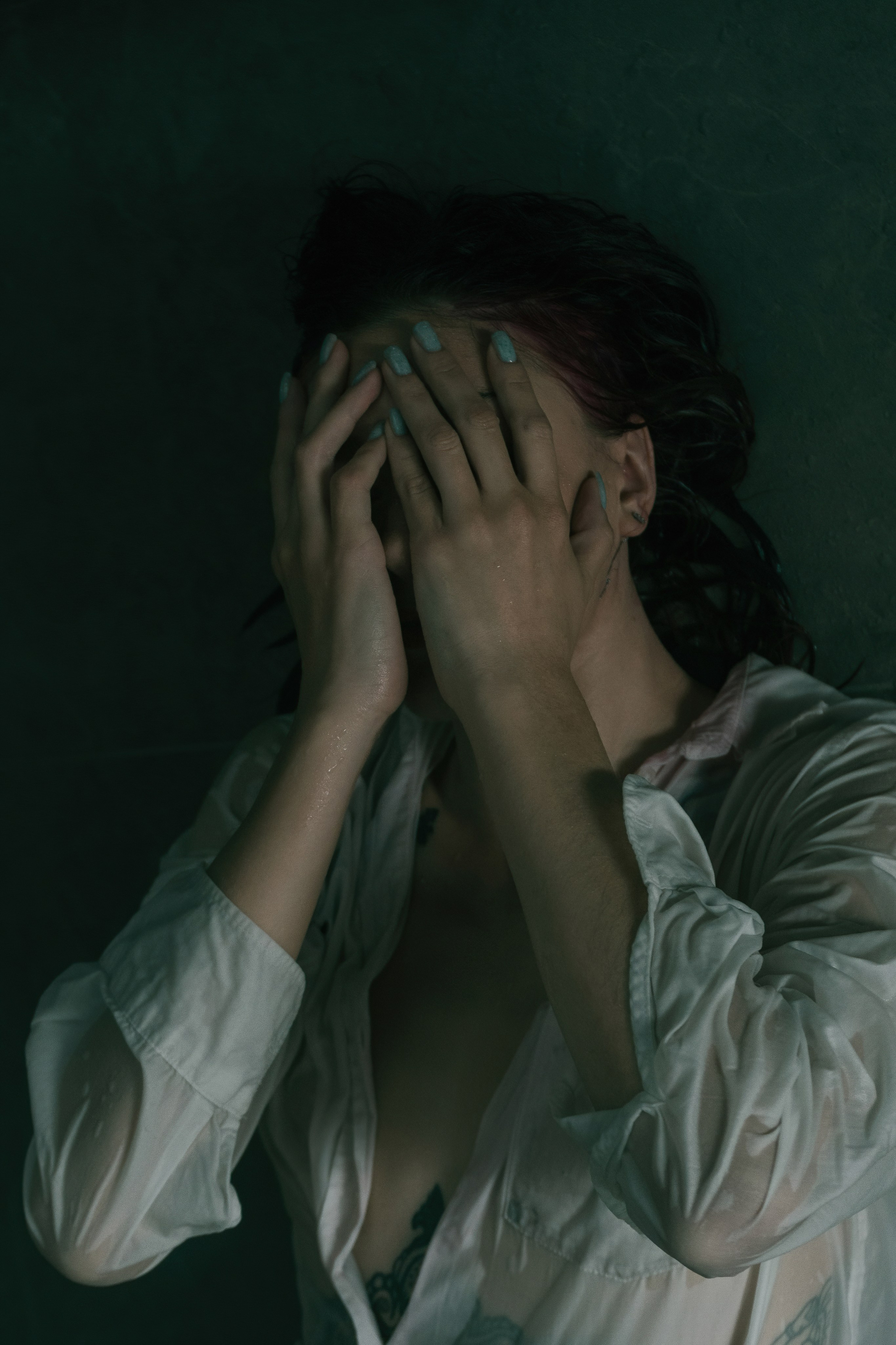 Девушка закрывает лицо руками. Съёмка в низком ключе, эмоциональная фотосессия.