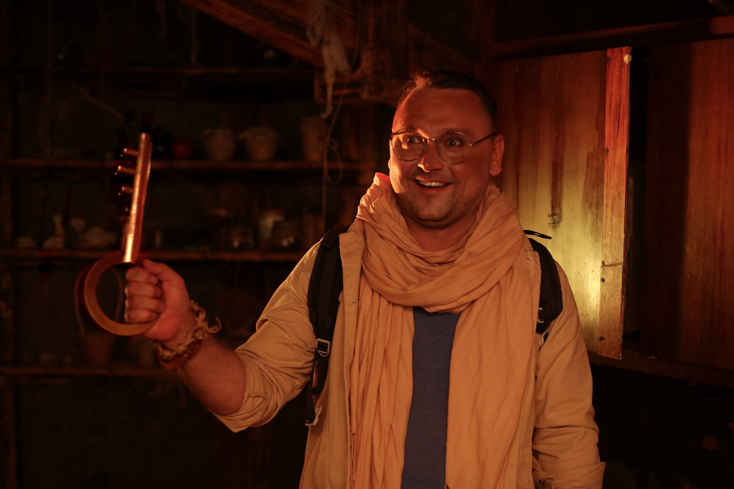 Мужчина в костюме исследователя держит ключ в темной комнате