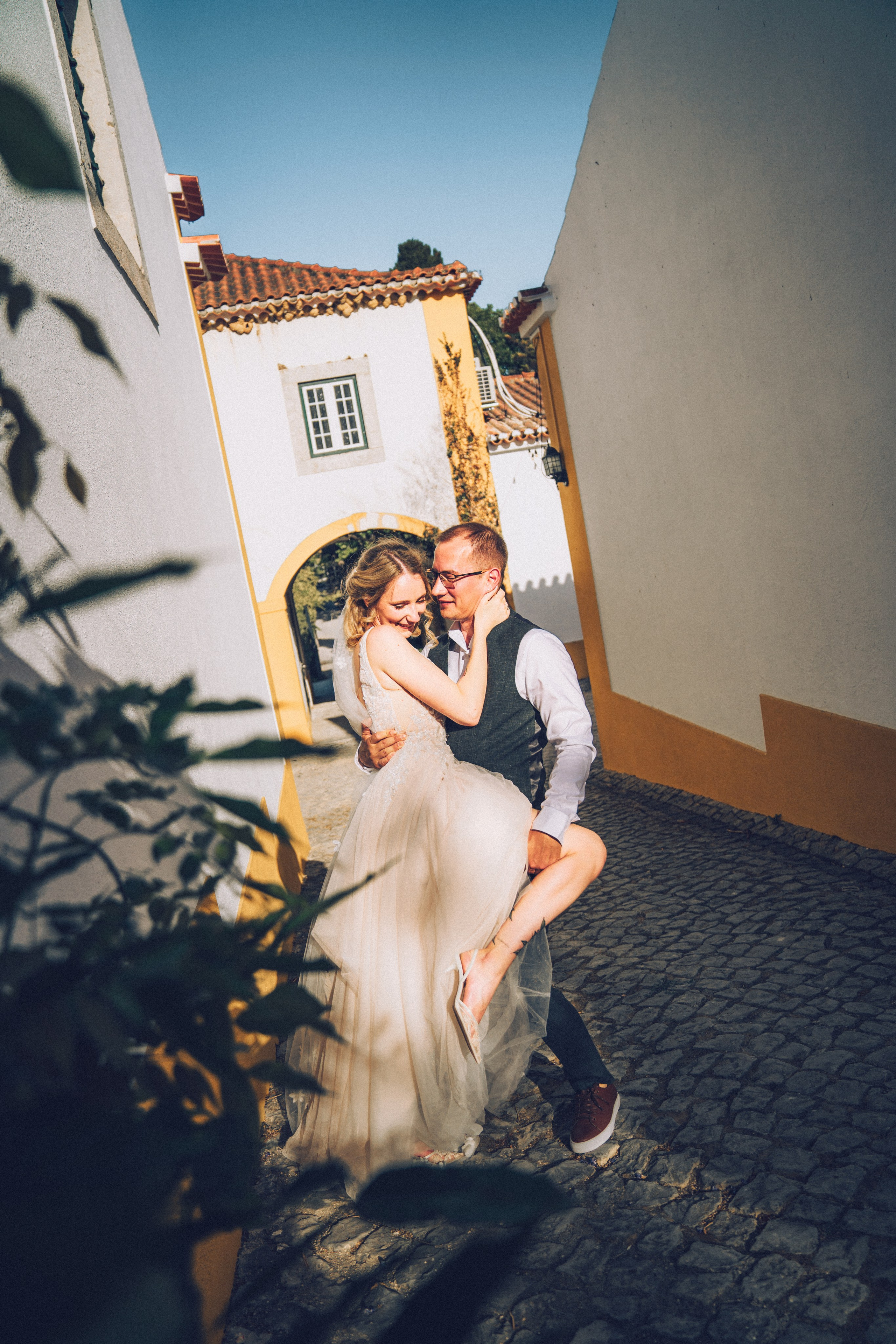 Влюбленная  пара жених и невеста целуется и обнимаются на фоне старинных улочек Португалии