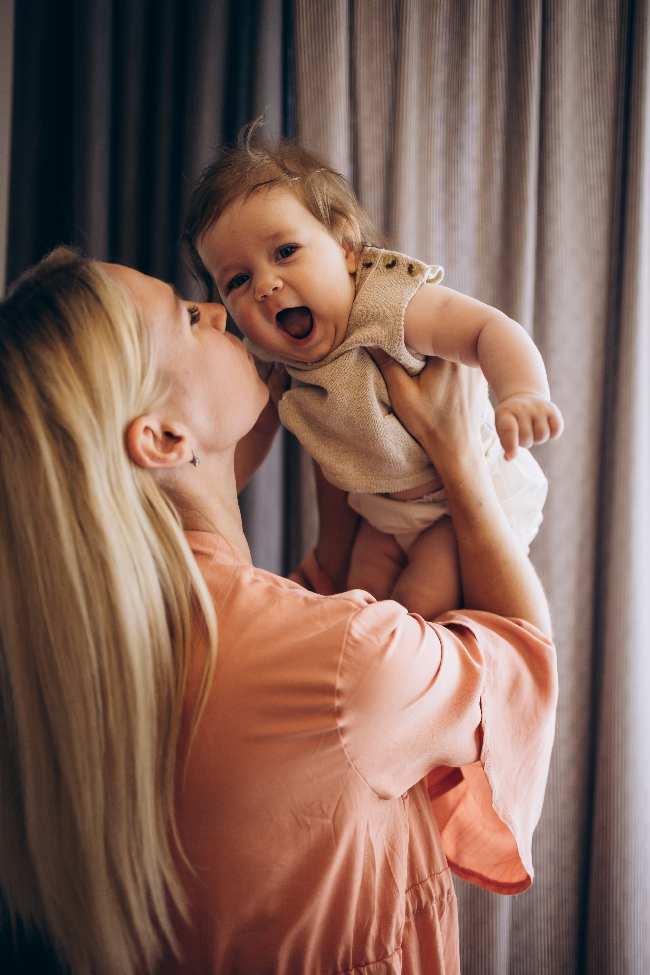 мама подняла над собой малышку и нежно поцеловала