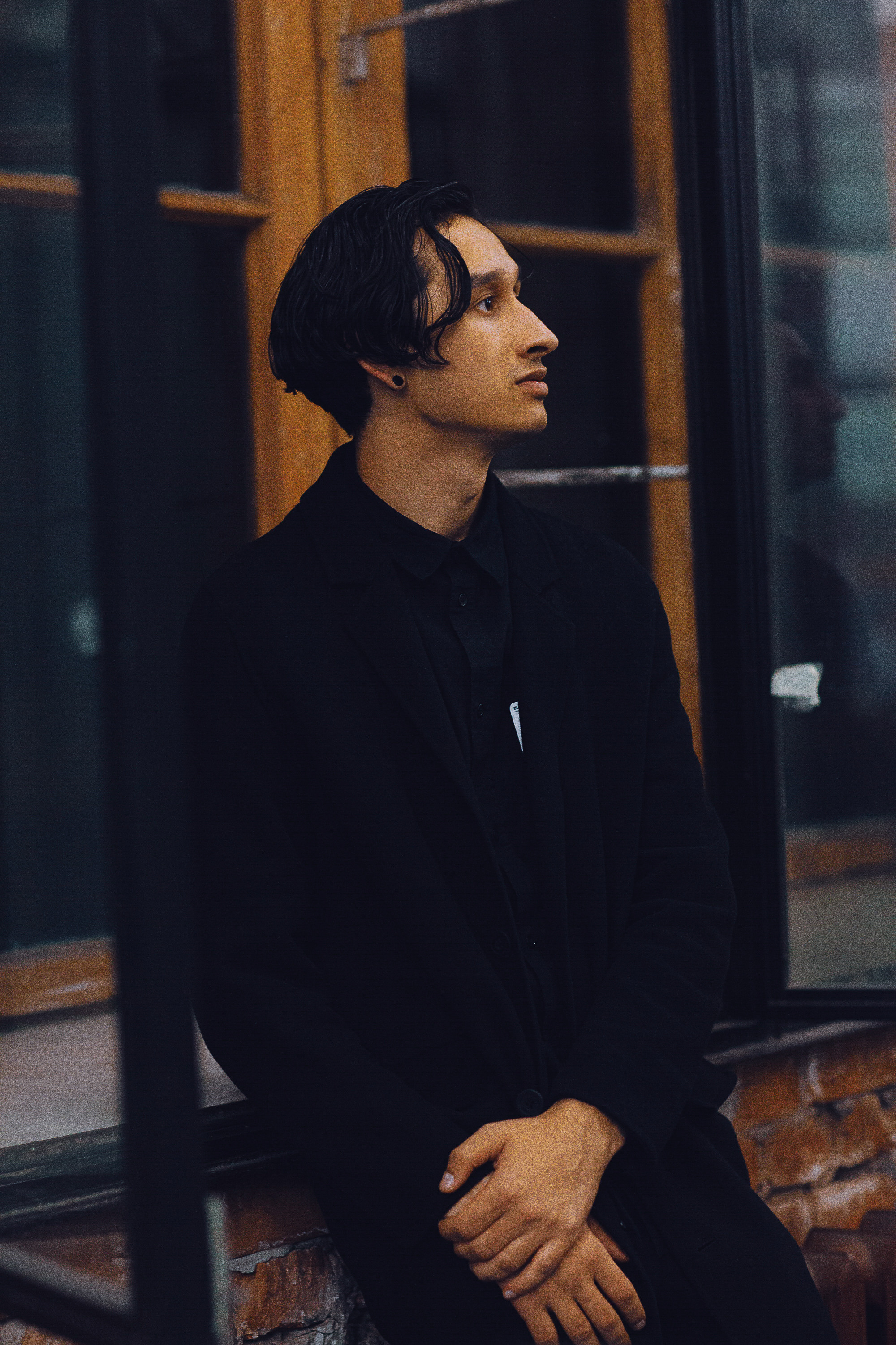 Молодой человек в черной одежде в помещении с окнами