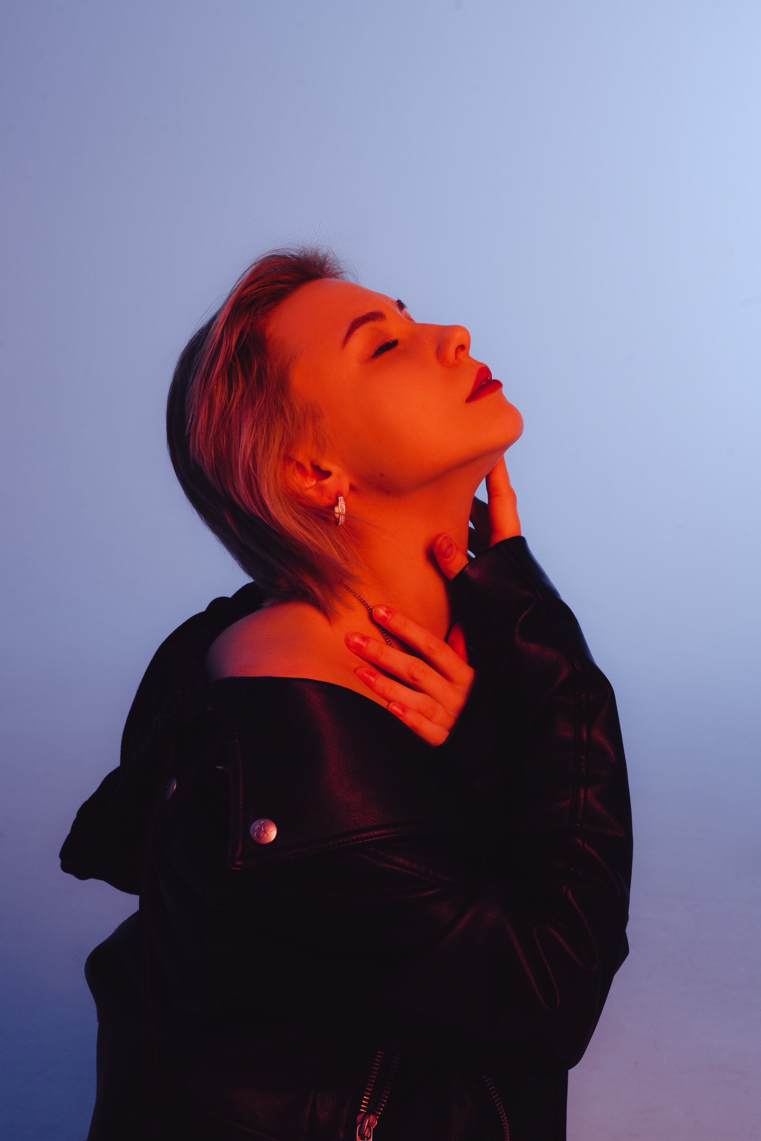 Девушка с короткой стрижкой в профиль с красной подсветкой на синем фоне 