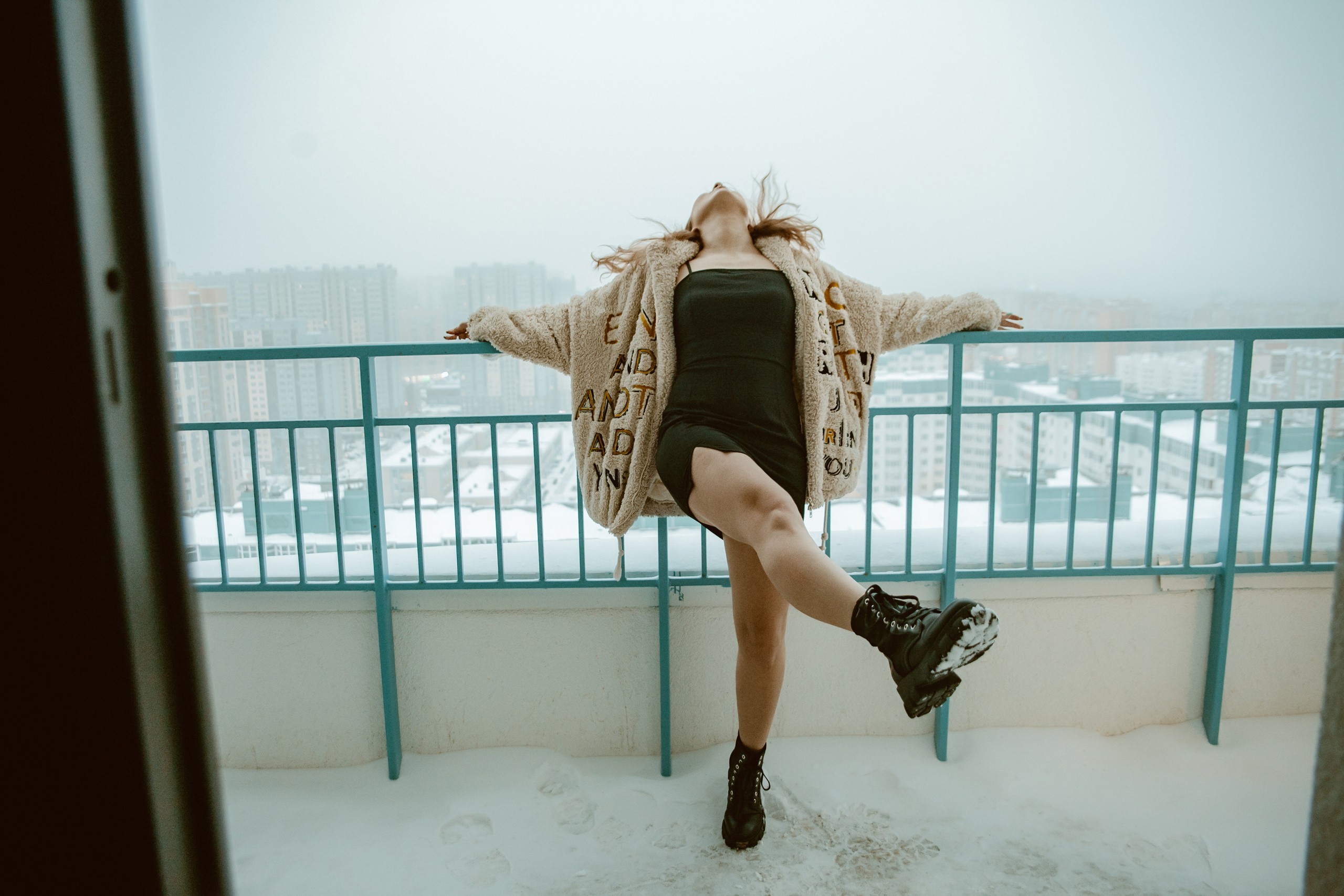 Девушка в шубе стоит на балконе