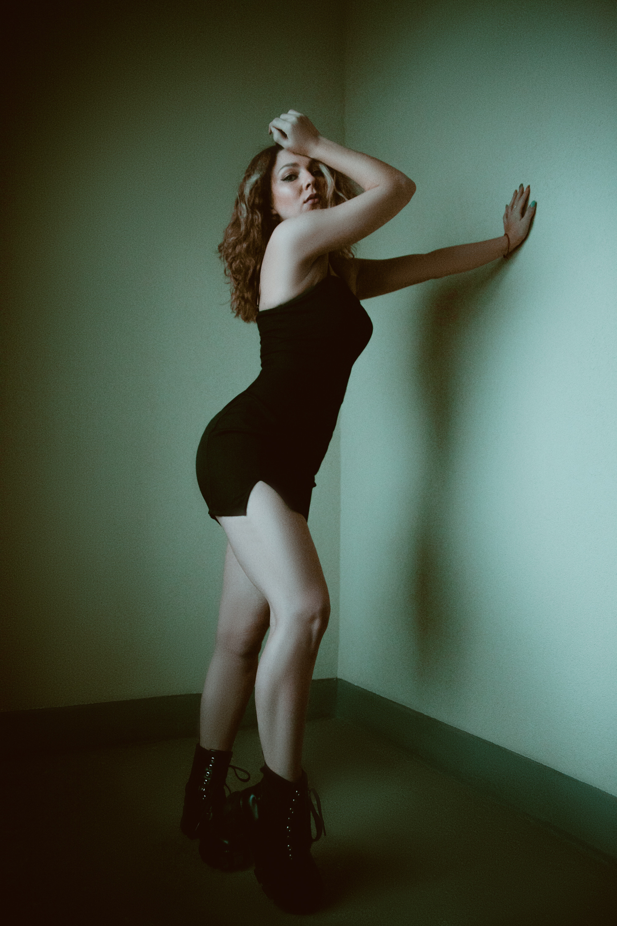 Девушка в черном платье на фоне стены