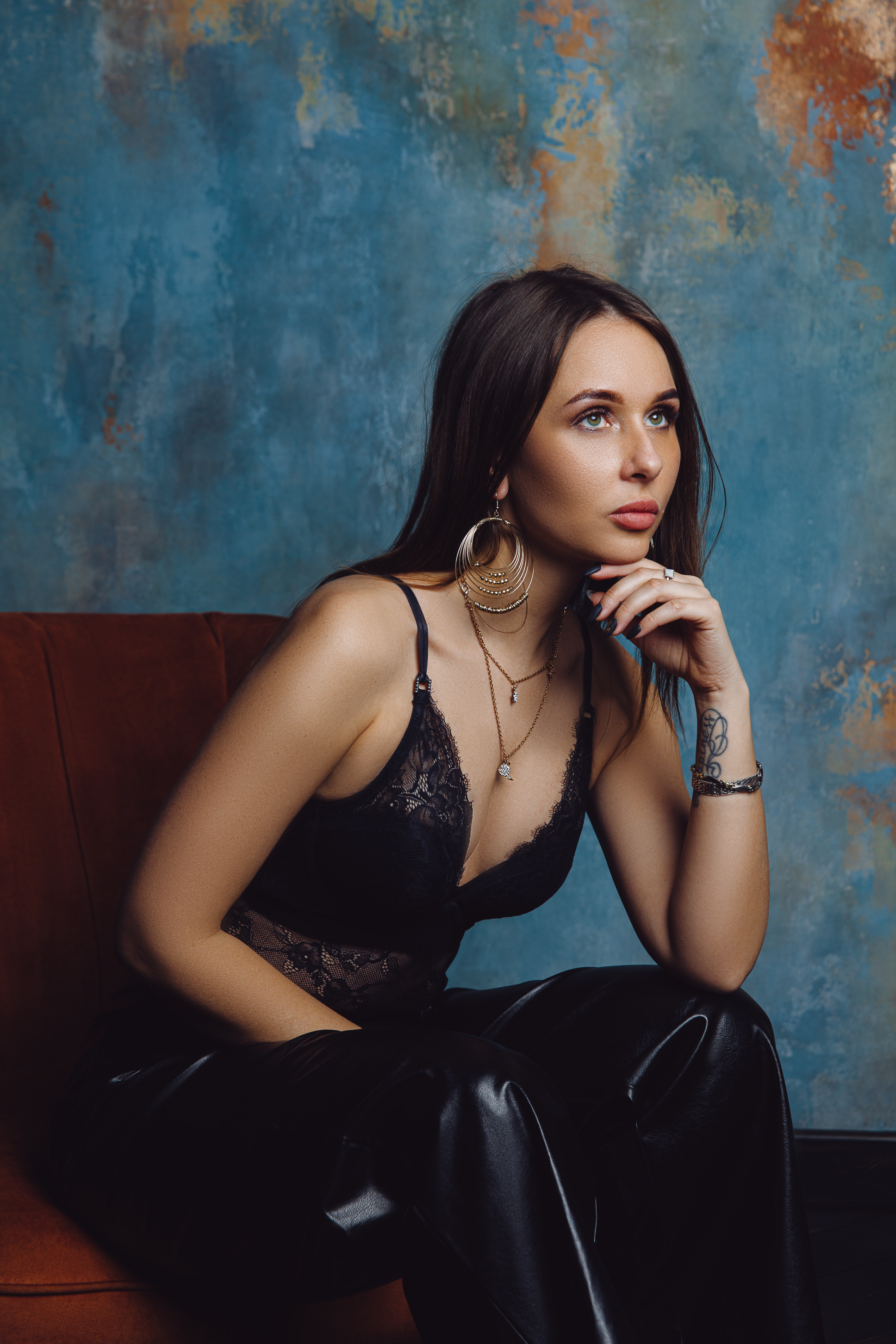 Девушка в черном сидит на фоне текстурной стены