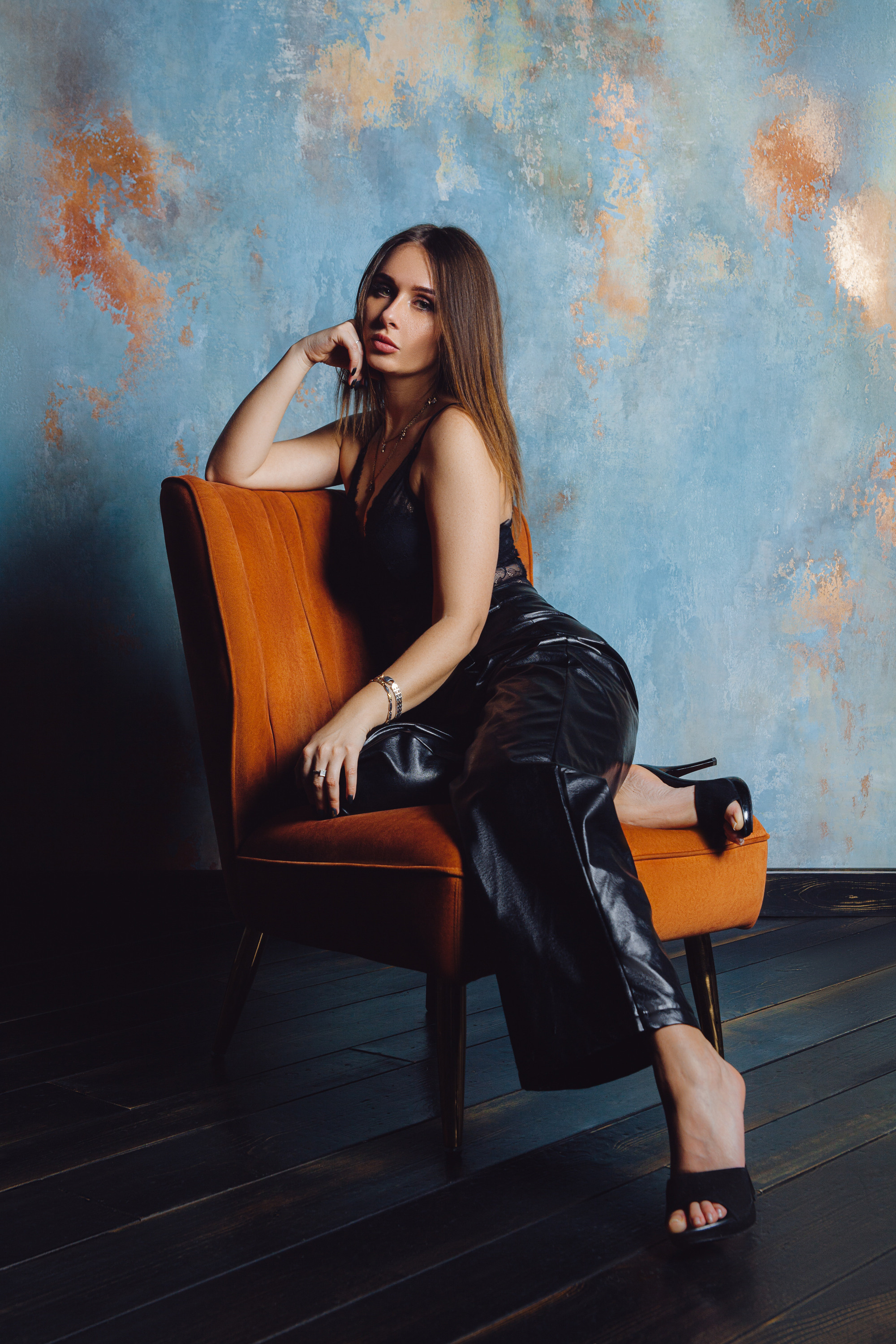 Девушка в черной одежде сидит на оранжевом кресле