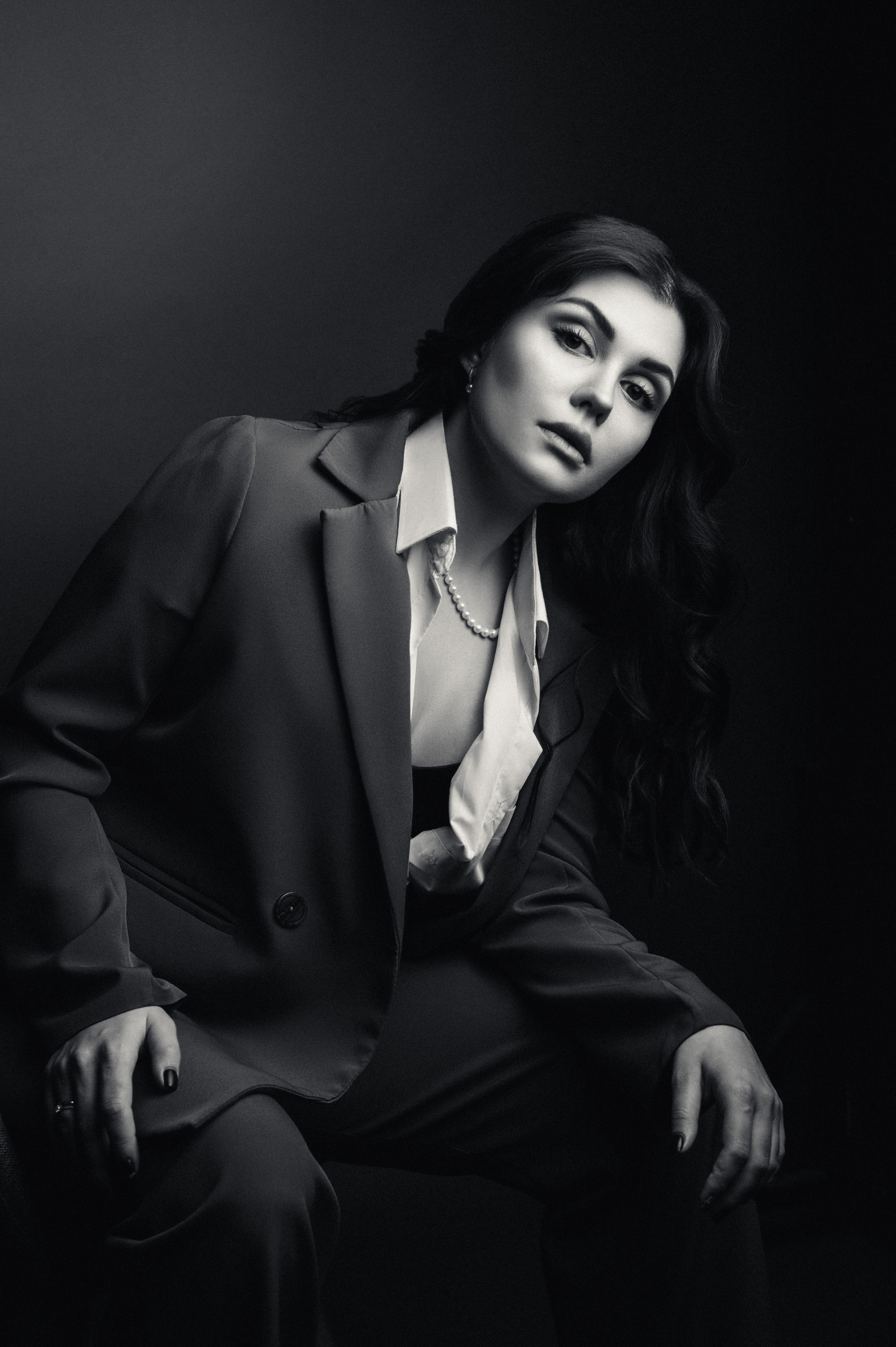 Черно-белый портрет девушки в брючном костюме в фотостудии